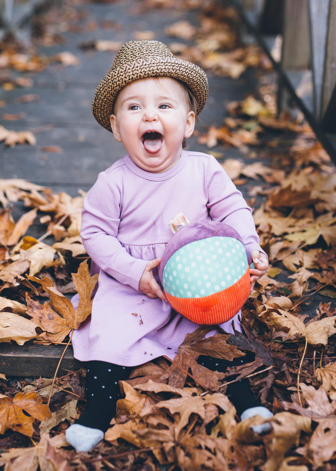 baby-wearing-a-hat-and-smiling-huge-with-a-ball-in-hands.jpg
