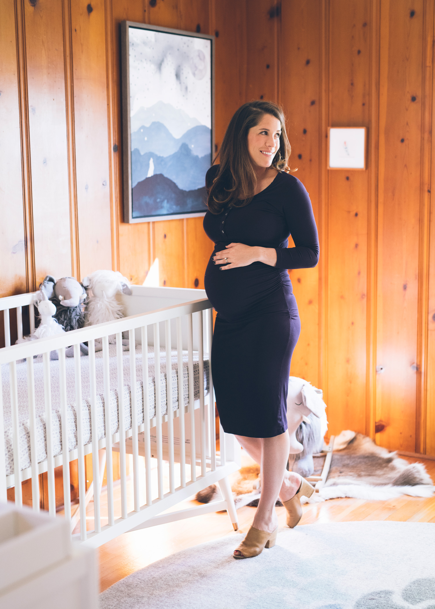 pregnant-woman-standing-near-a-crib-in-mid-century-modern-nursery.jpg