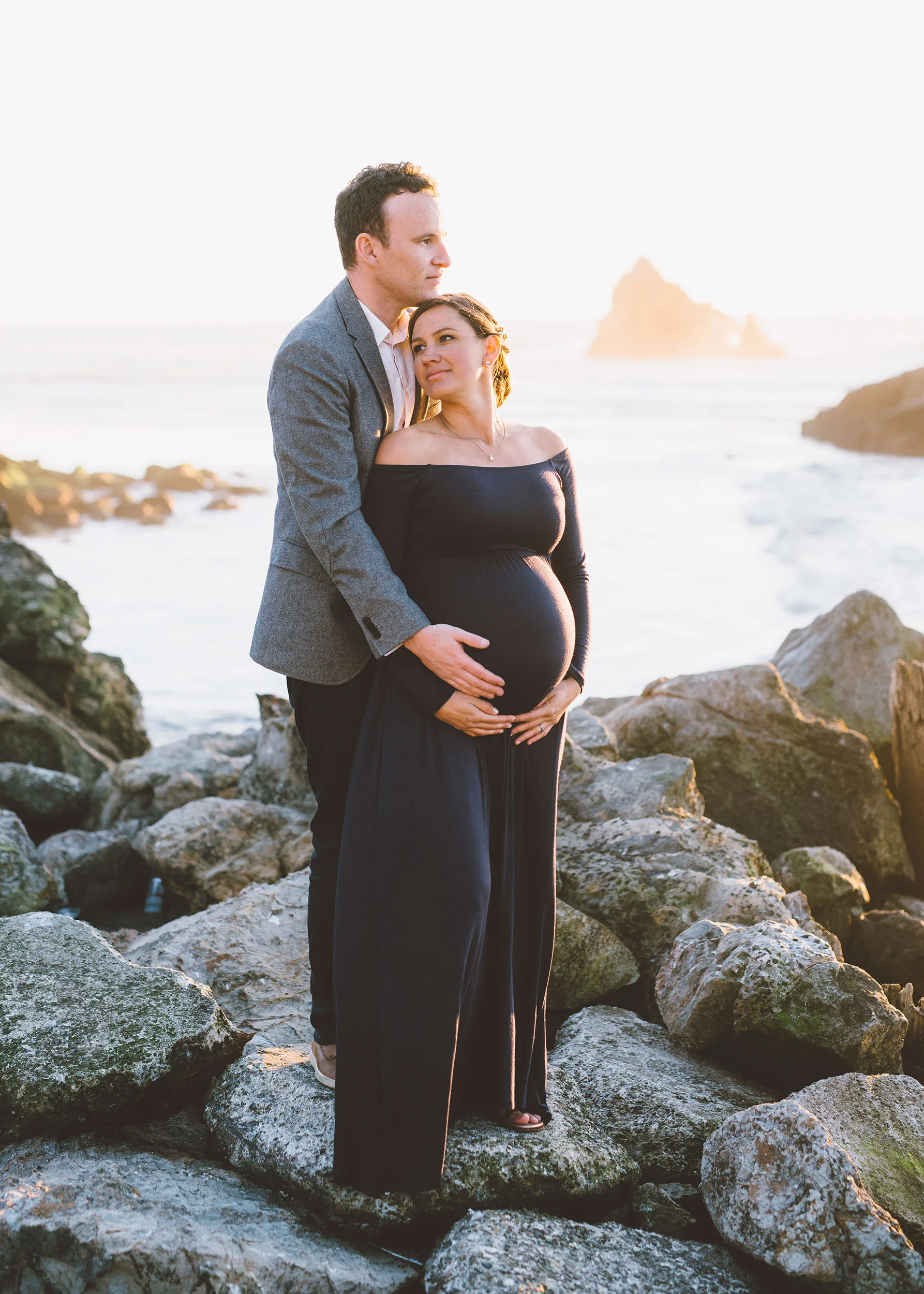 expectant-couple-embracing-during-sunset-over-the-ocean.jpg