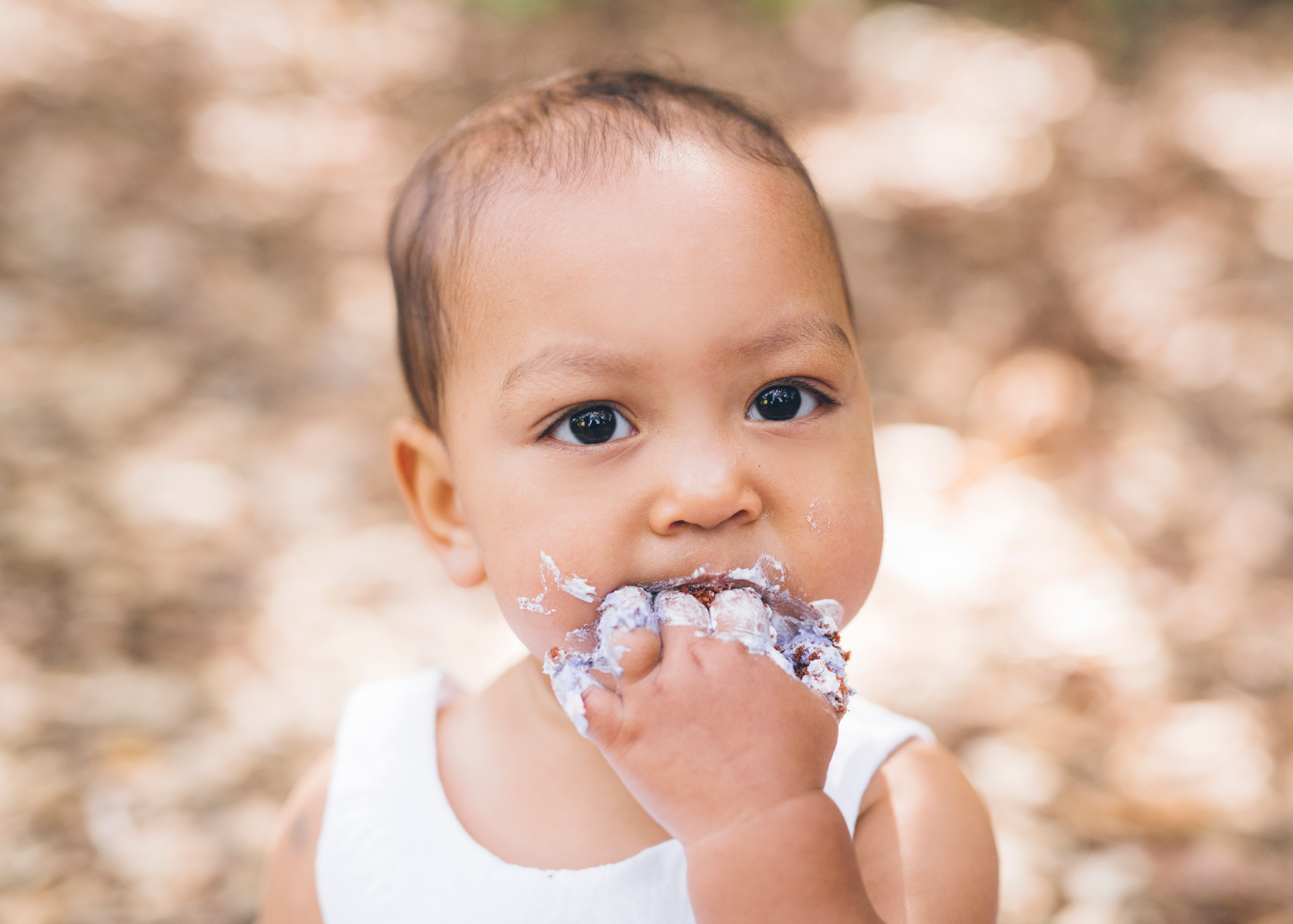 baby-eating-cake-during-her-one-year-old-portrait-session.jpg