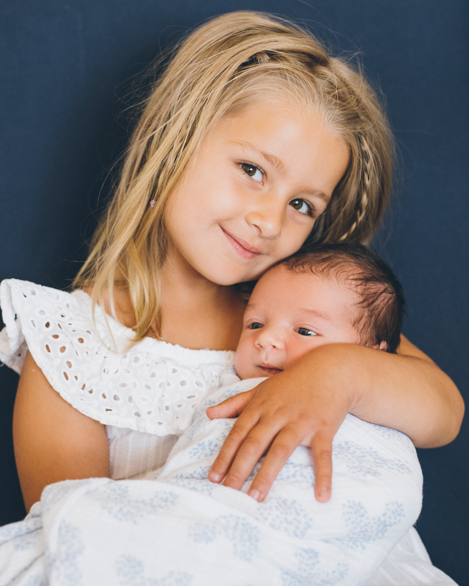 photo-of-a-big-sister-holding-baby-brother.jpg