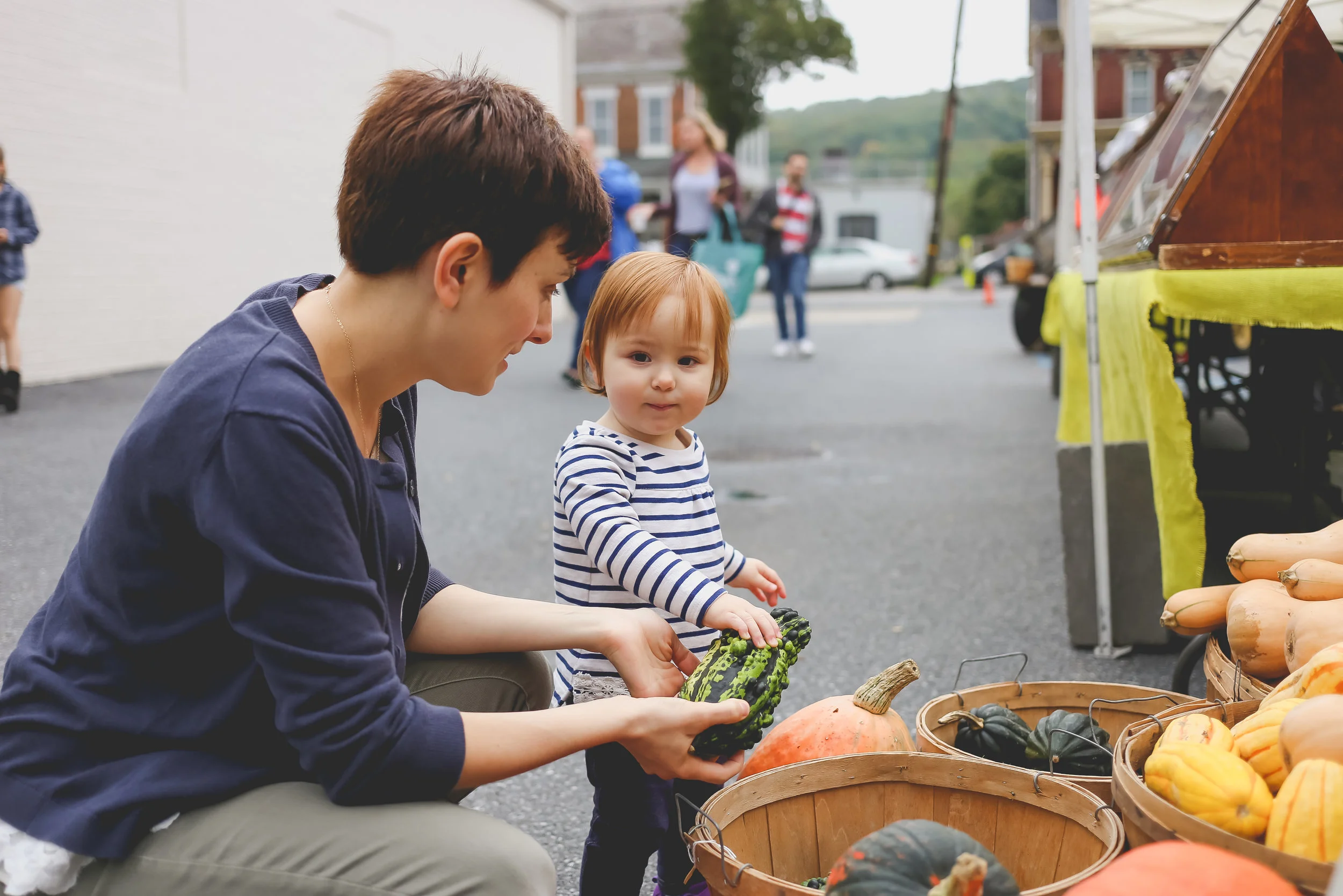 Toddler shopping for gourds with her mother at the Emmaus Farmer's Market. Lehigh Valley Family Photography.
