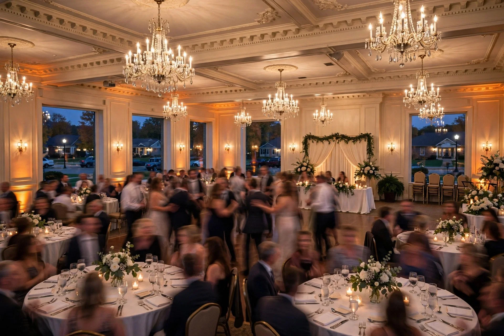 Elegant wedding reception inside a classic banquet ballroom in Villa Park, Illinois, with chandeliers, white linens, warm uplighting and guests dancing