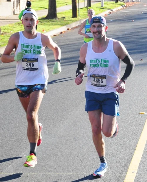 Doug running with John Williams to massive personal bests at CIM 2017. Photo: TFTC . 