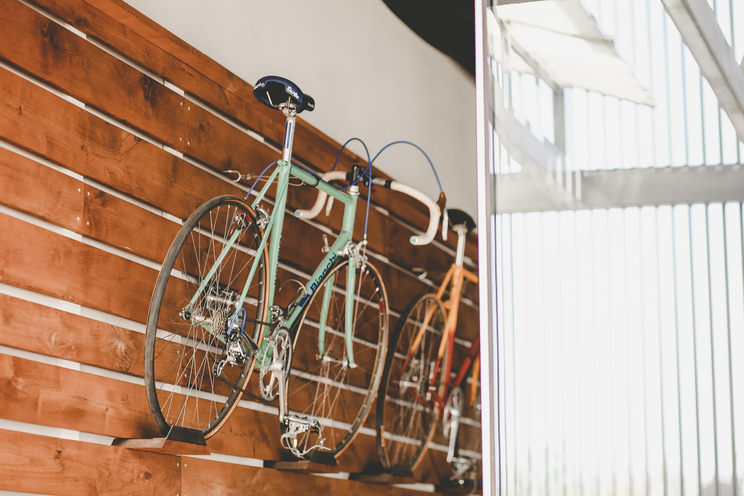 The mounting of three of Curtis' road bikes was a must decided early on. As soon as the wood wall was envisioned, the bicycles were easily imagined as the main artwork to be on display. Curtis was formerly a professional cyclist and as he competed and toured the world, his love for coffee and the cycling community led him to venture into starting his coffee shop. The bikes help tell that story. 