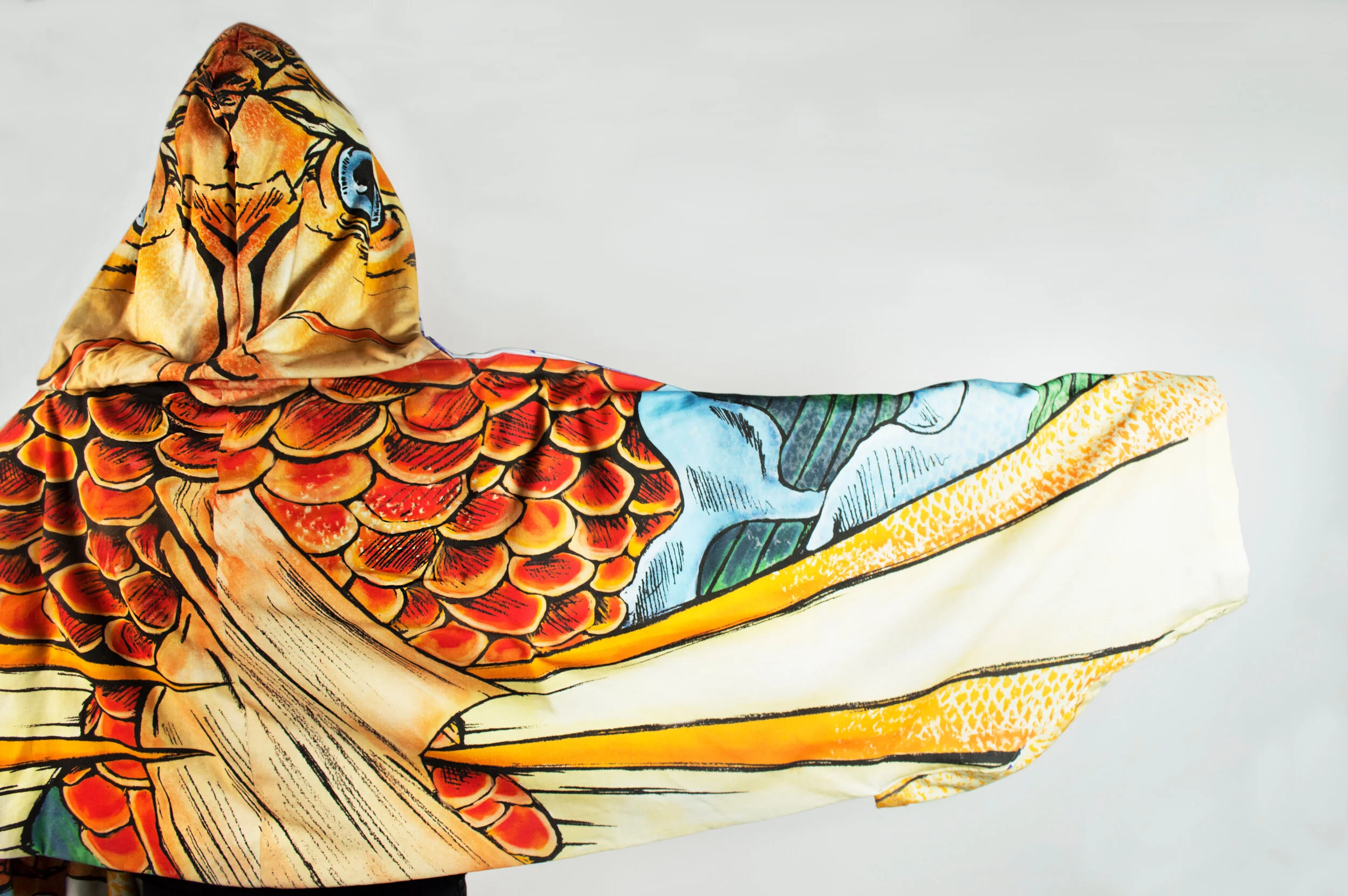 Close-up of a colorful silk scarf featuring a butterfly and floral pattern, draped against a plain background.