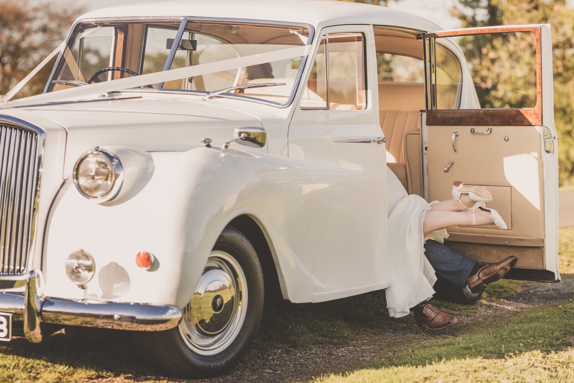 Bride and groom's feet sticking out of a wedding car at Somerford Hall