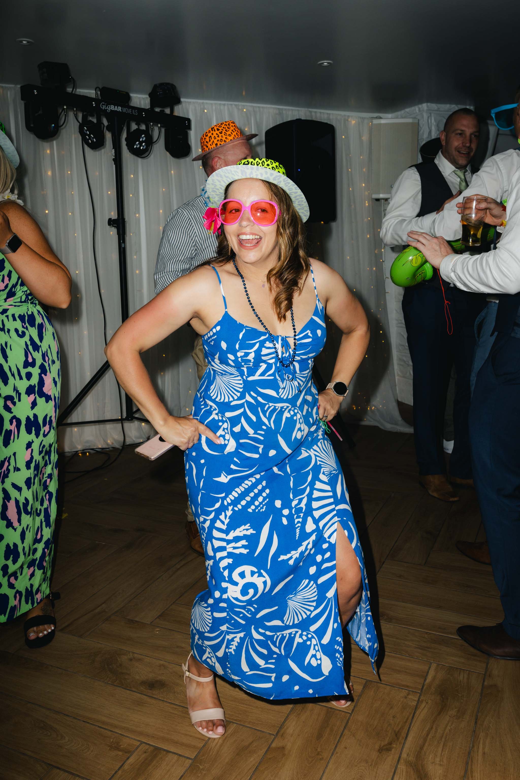 Female wedding guests wearing silly sunglasses on dance floor at Watermouth Cove Weddings