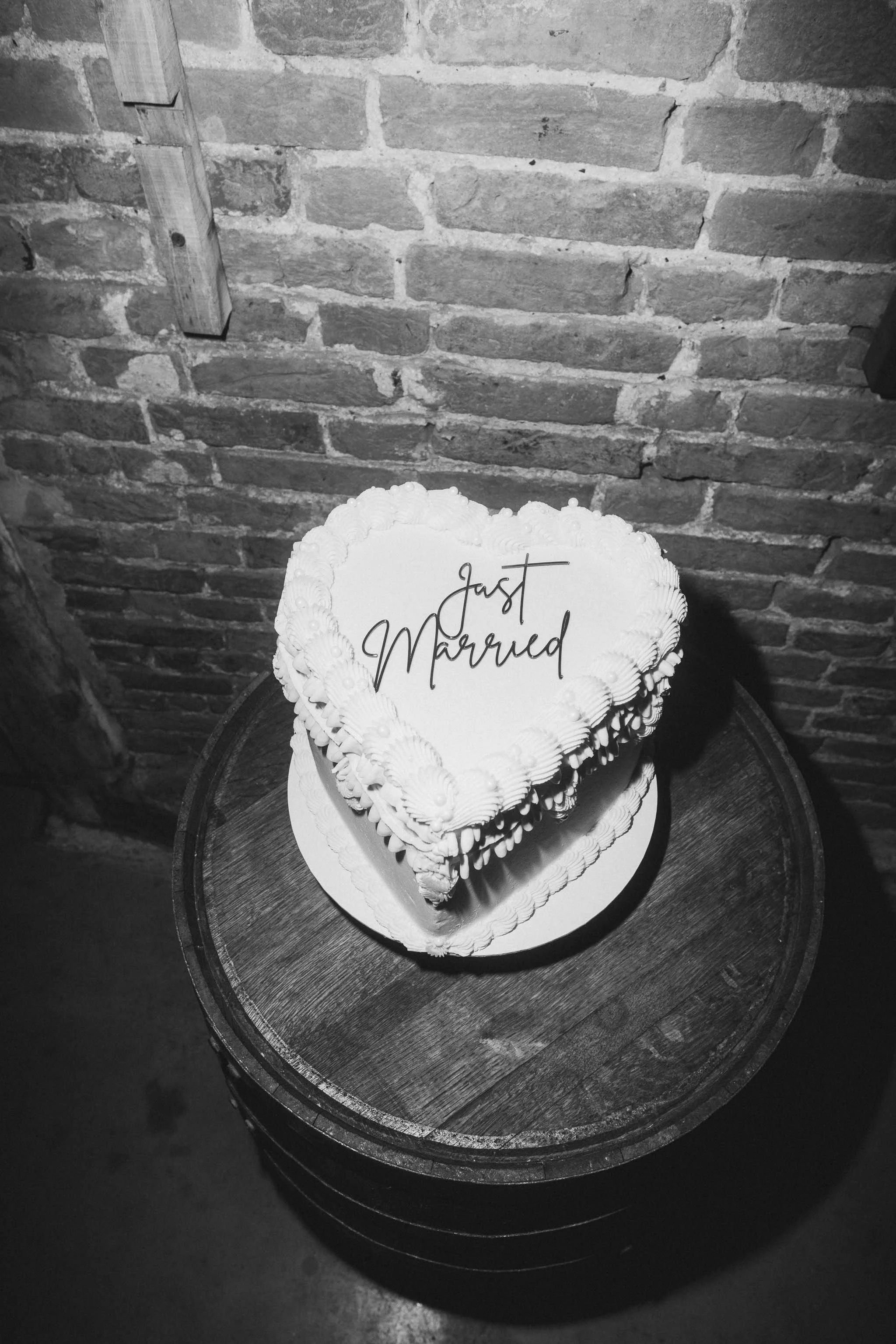 A vintage-style heart shaped wedding cake with pipped icing and black ‘just married’ text.