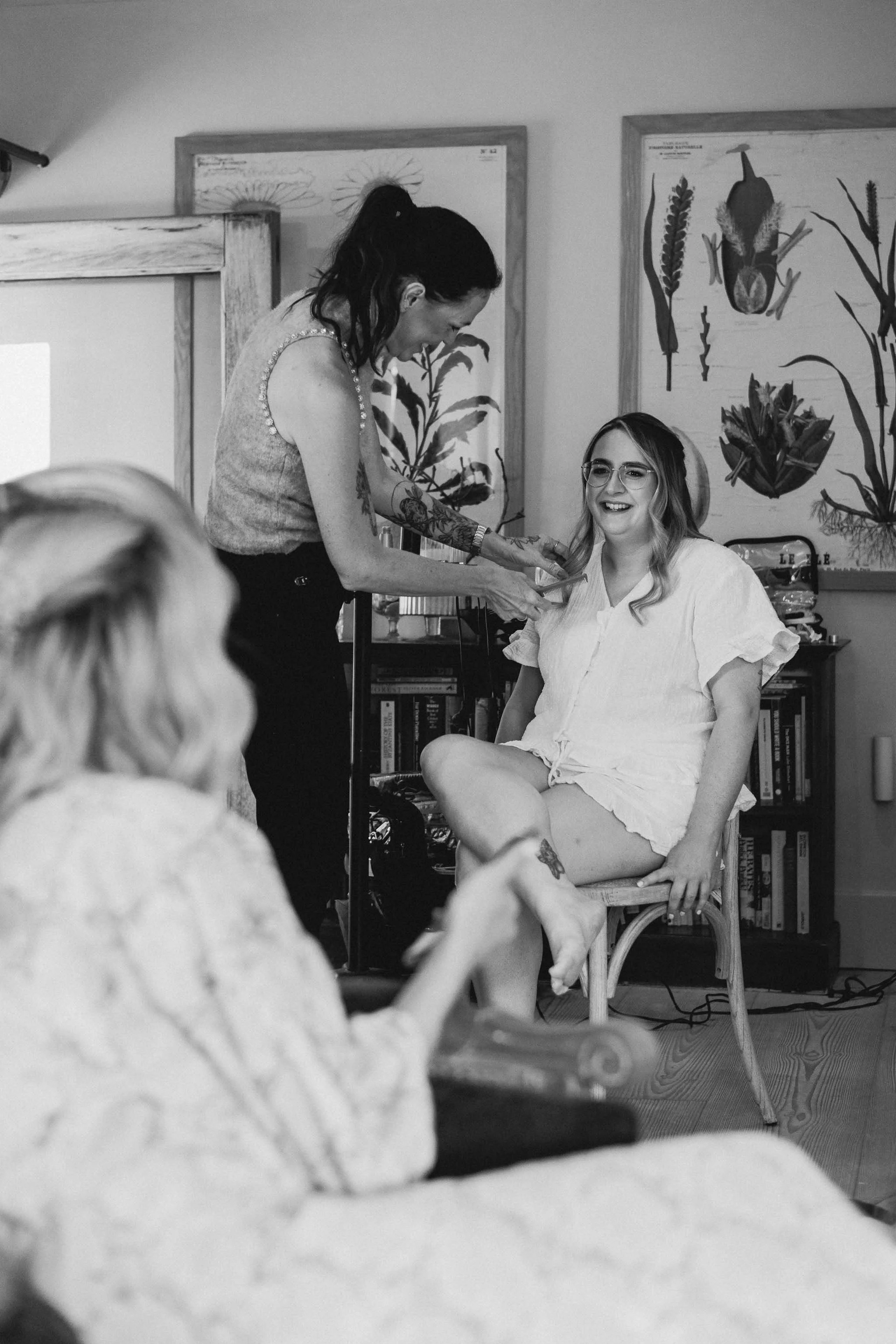 Bride smiling and chatting as she gets her hair done on her wedding morning.