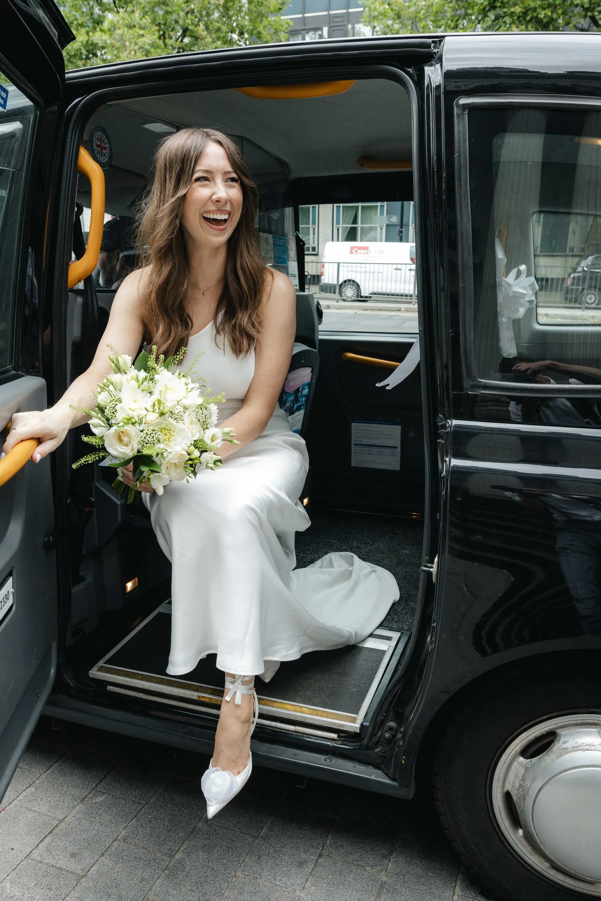 Bride smiling as she steps out of a London black cab outside Marylebone Town Hall.