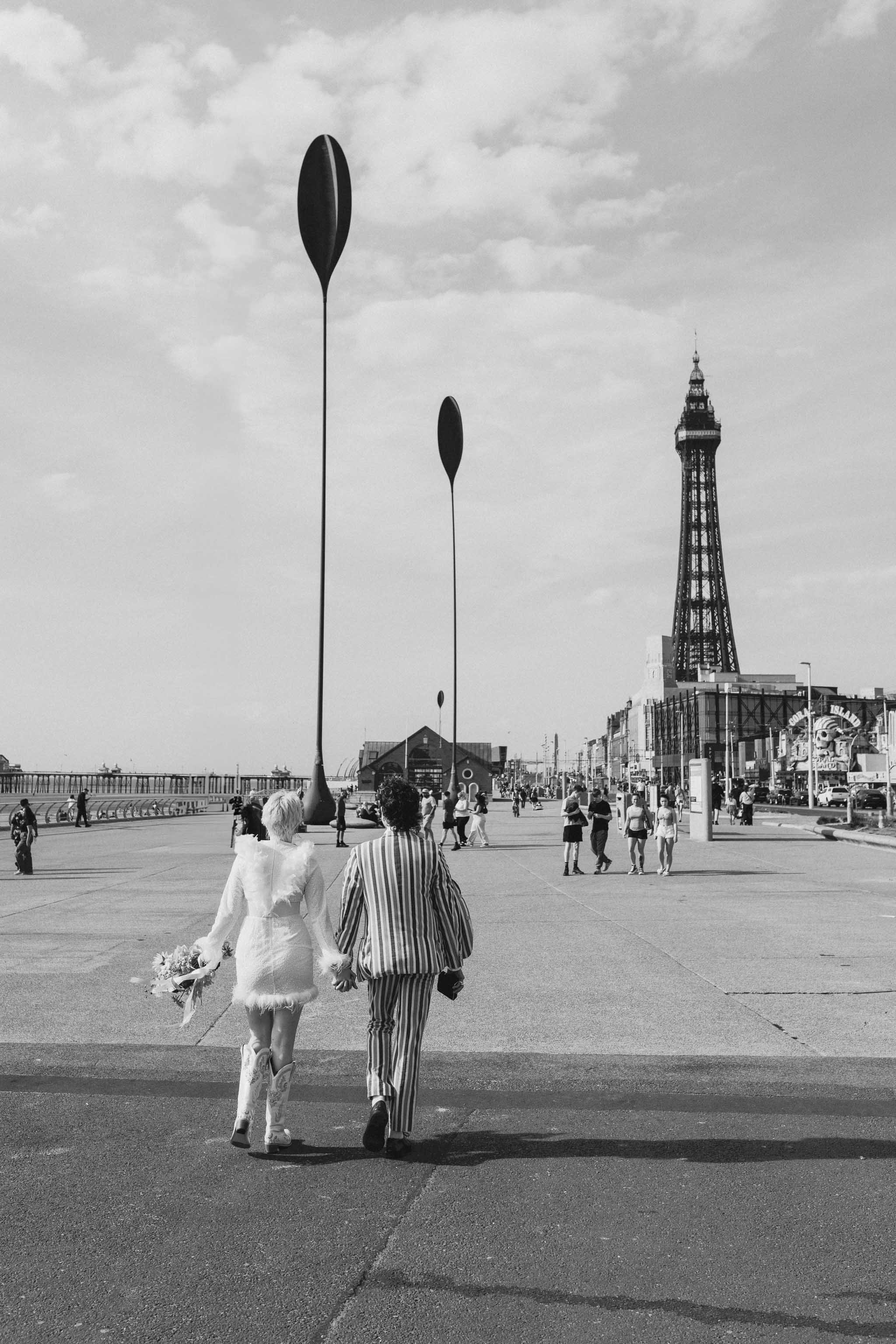 Couple walking along a seaside promenade during their intimate elopement