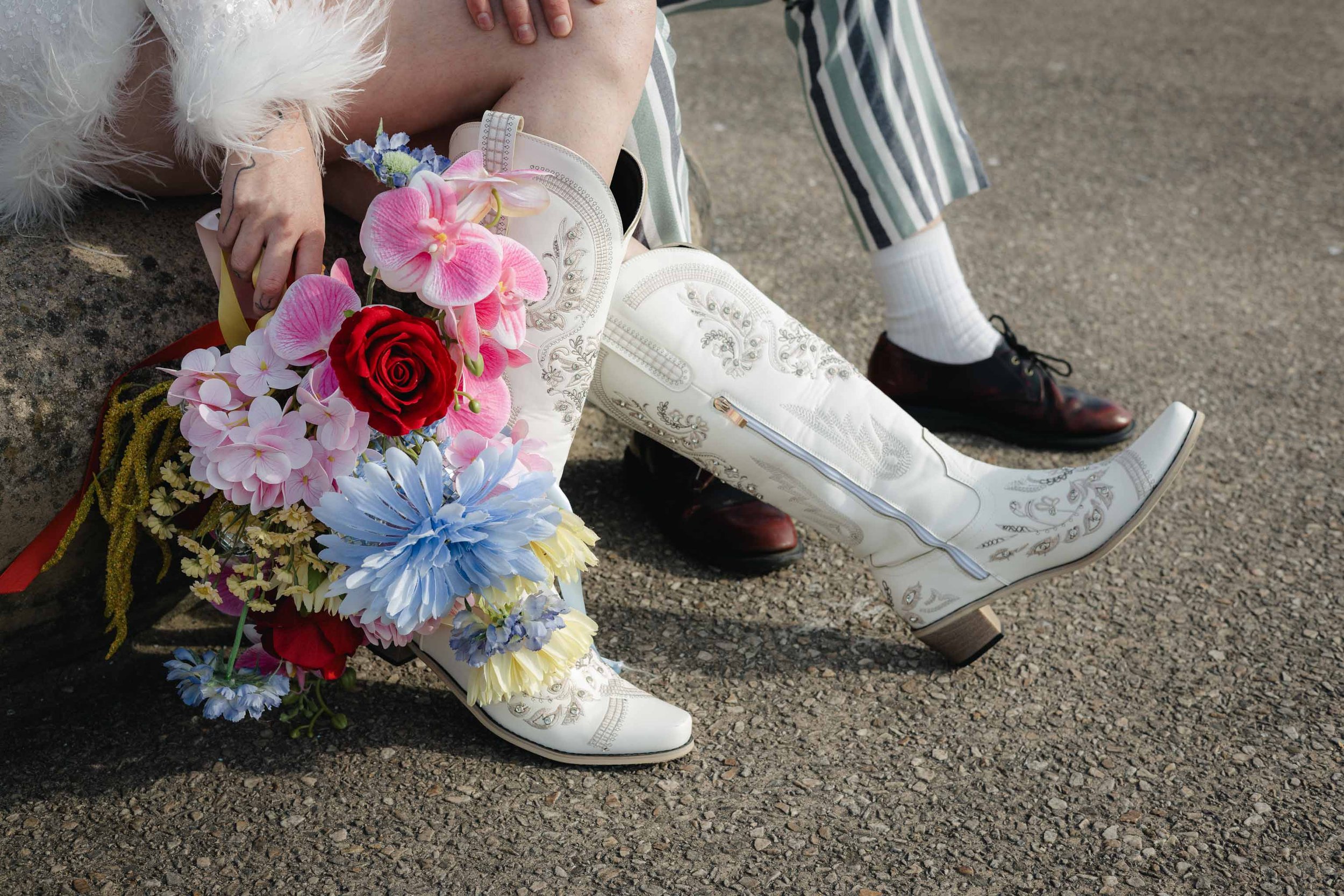 Close-up of a bride’s bouquet and cowboy boots in editorial wedding style