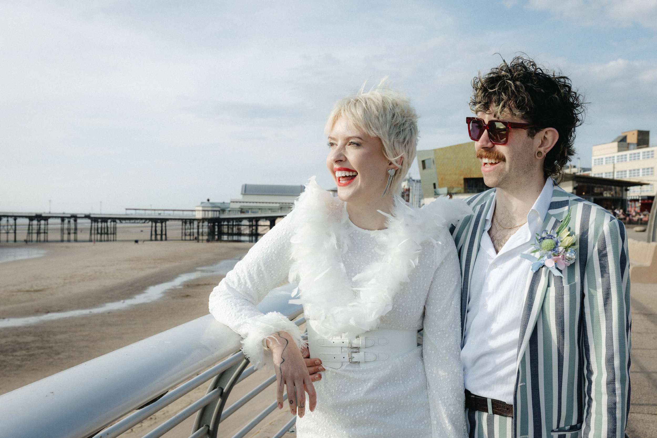 Bride and groom laughing naturally on a seaside promenade during their elopement wedding