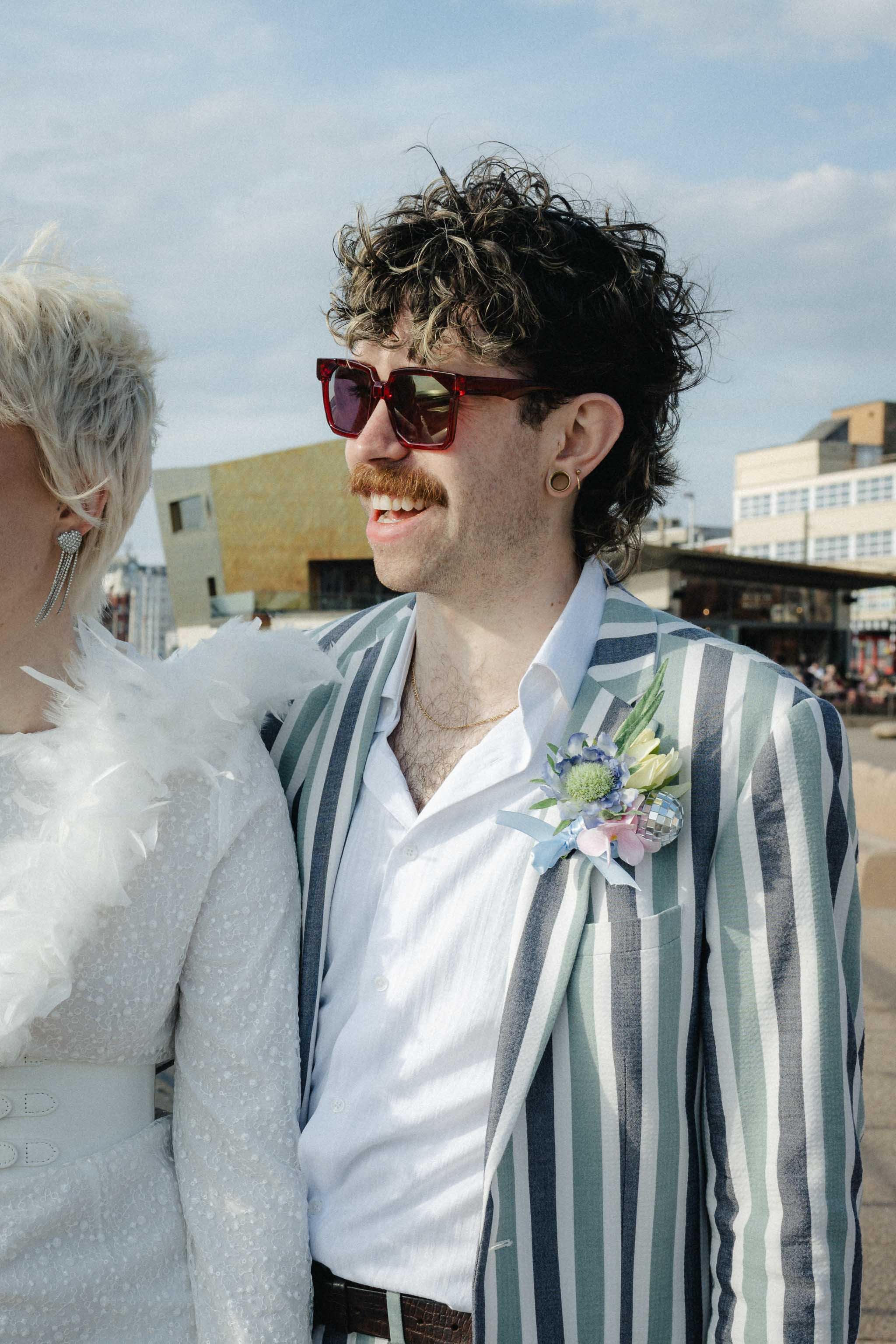 Groom laughing on Blackpool pier during couples portraits after an intimate elopement