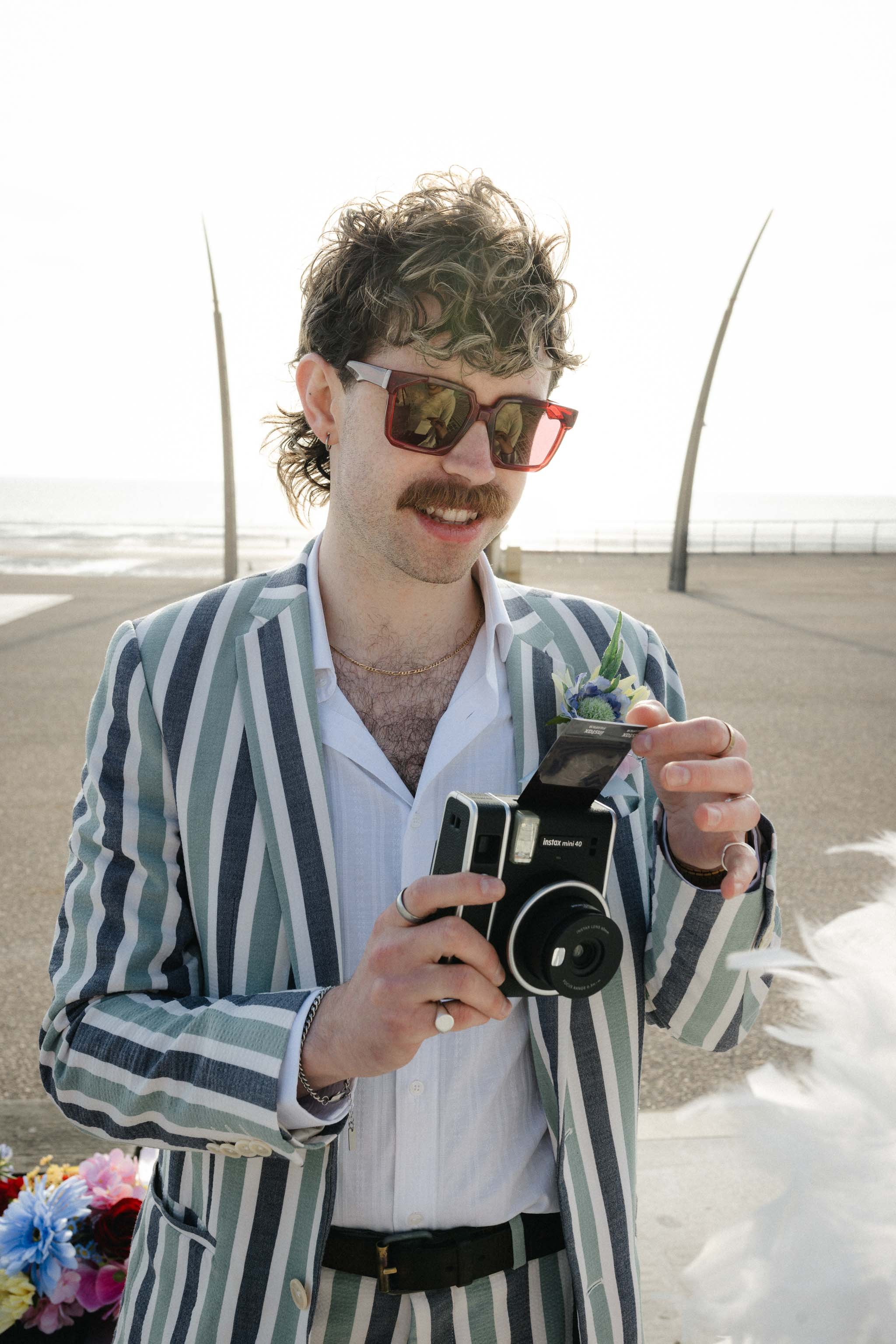 Groom taking a Polaroid photo on Blackpool pier