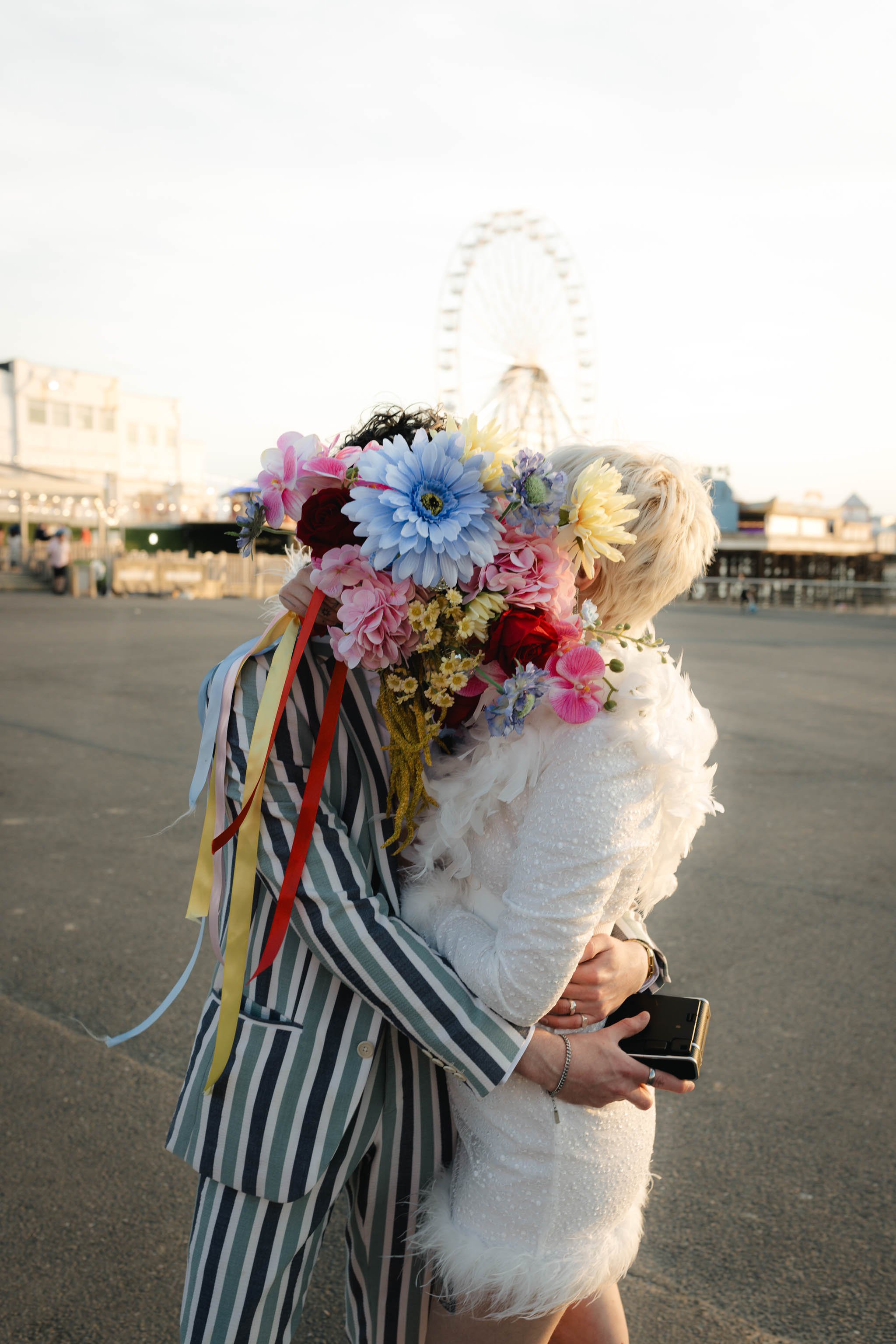 Bride and groom kissing behind a wedding bouquet in a seaside promenade