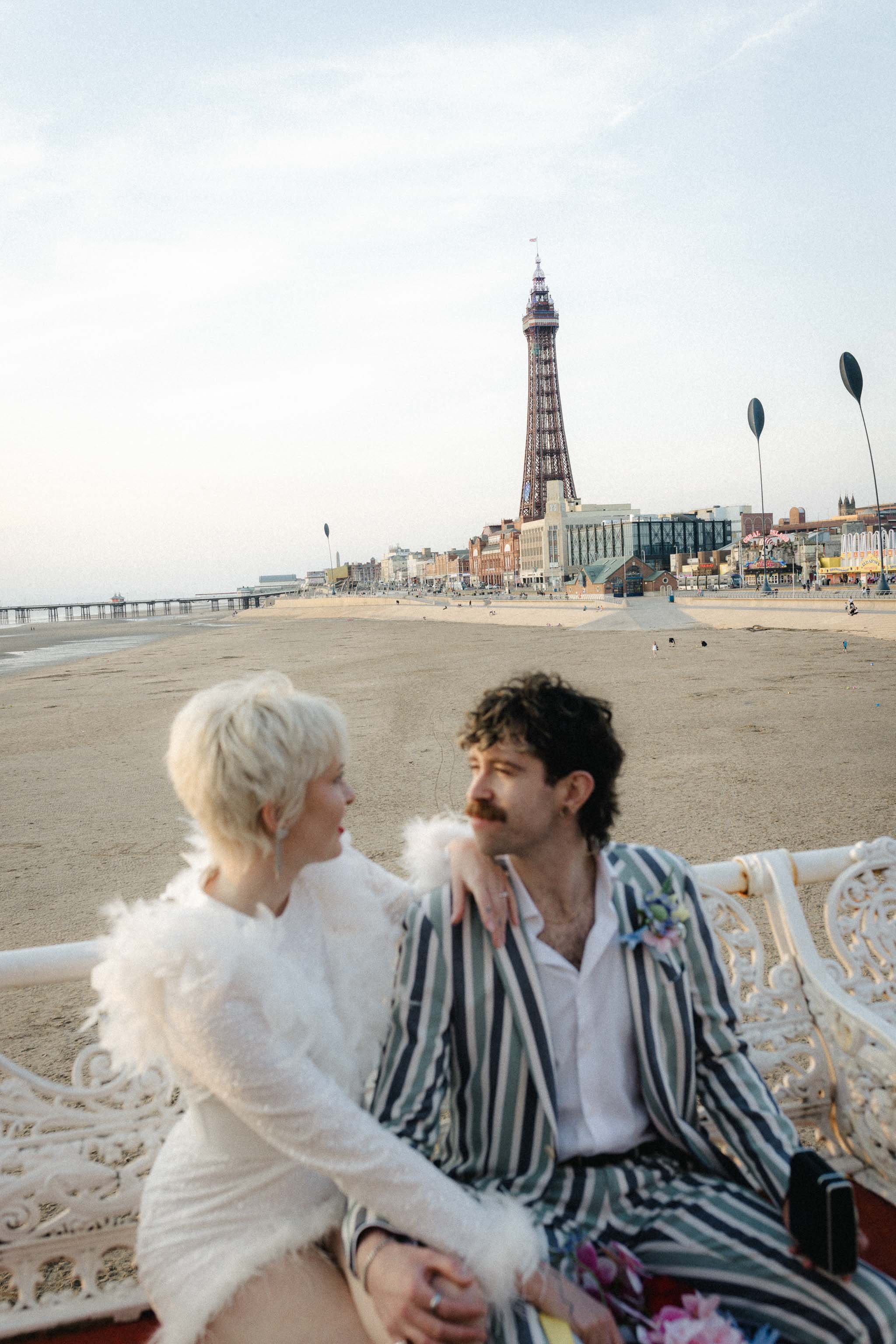 Newlywed portrait of a couple sat in front of the Blackpool Tower