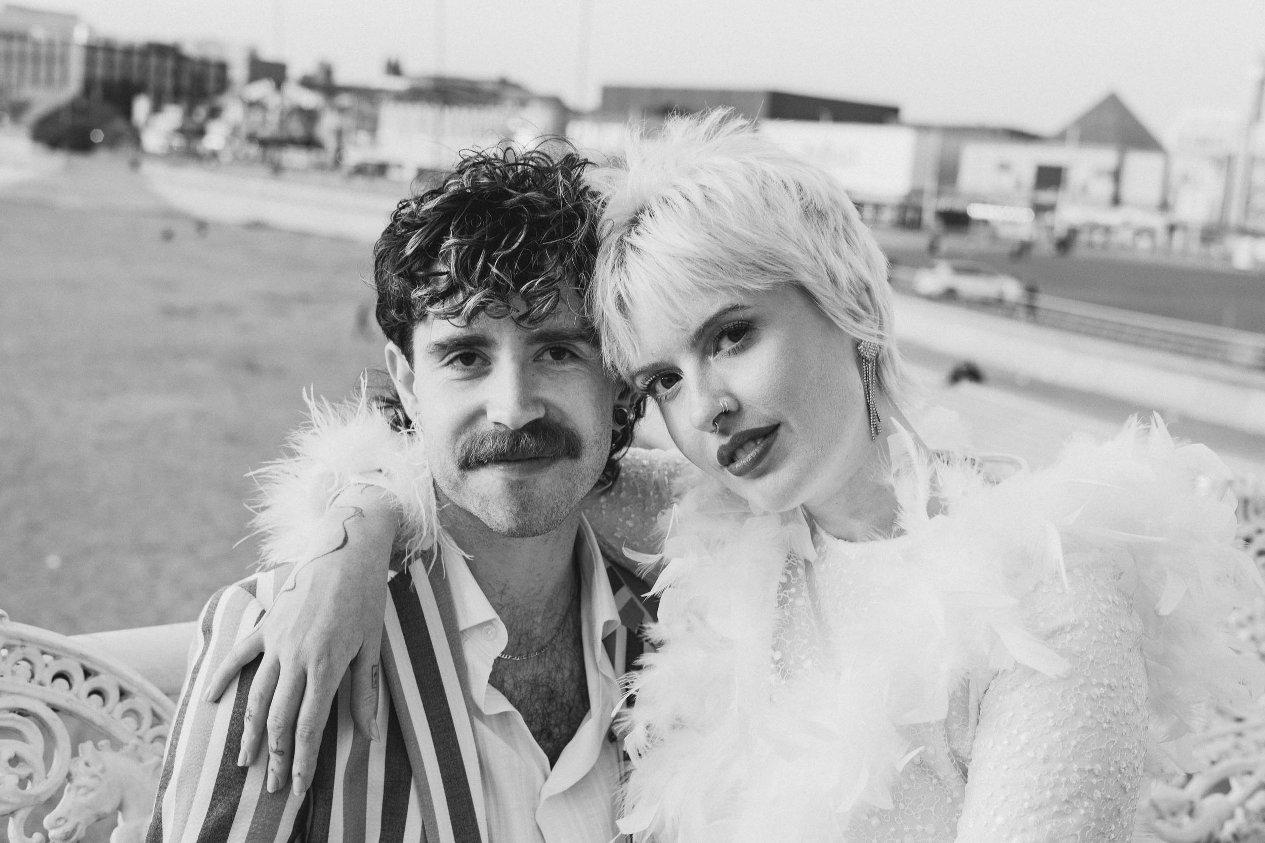 Couple sat cuddled up on a seaside promenade during their intimate elopement