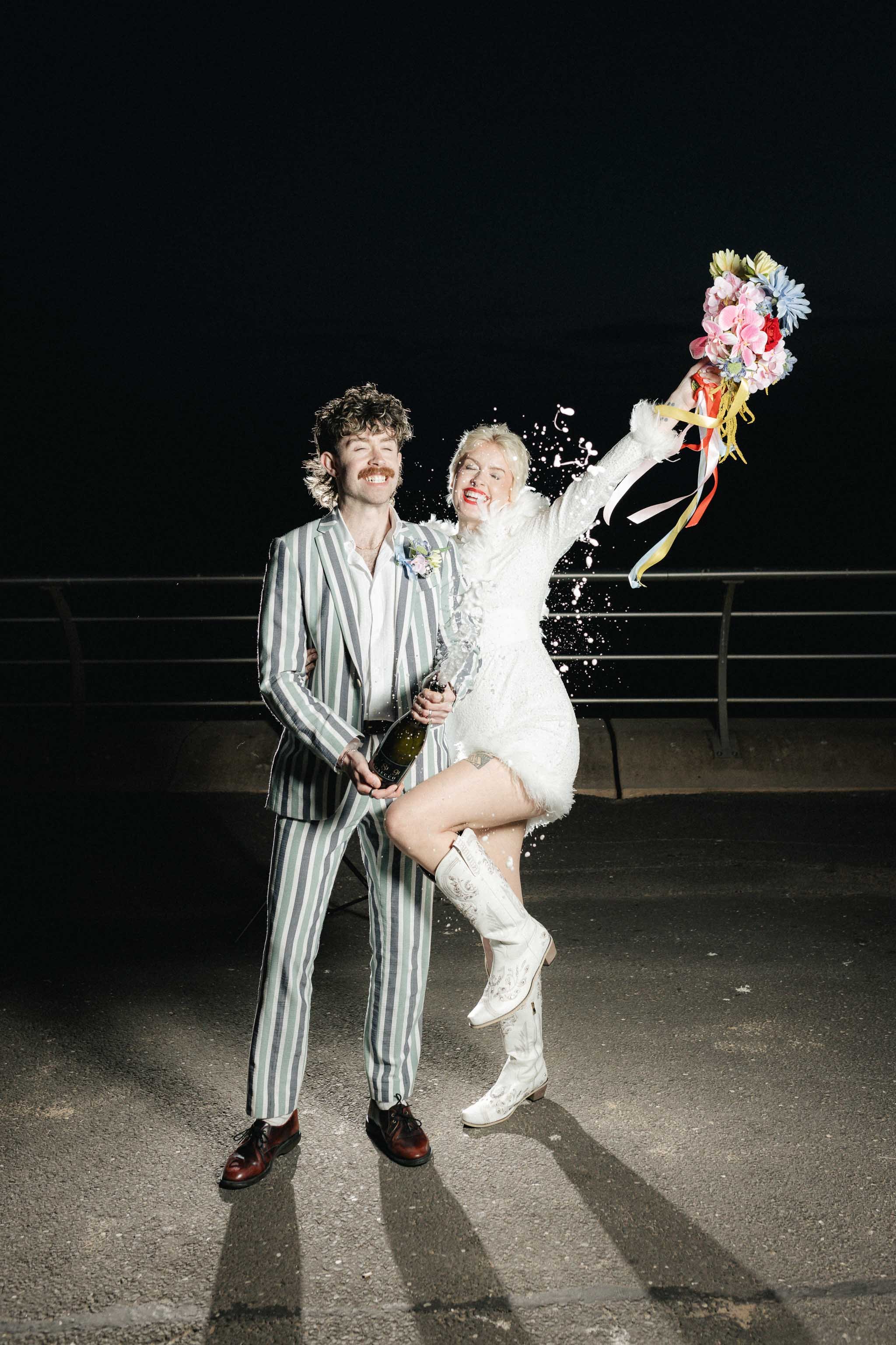 Editorial style photo of a bride and groom champagne spray