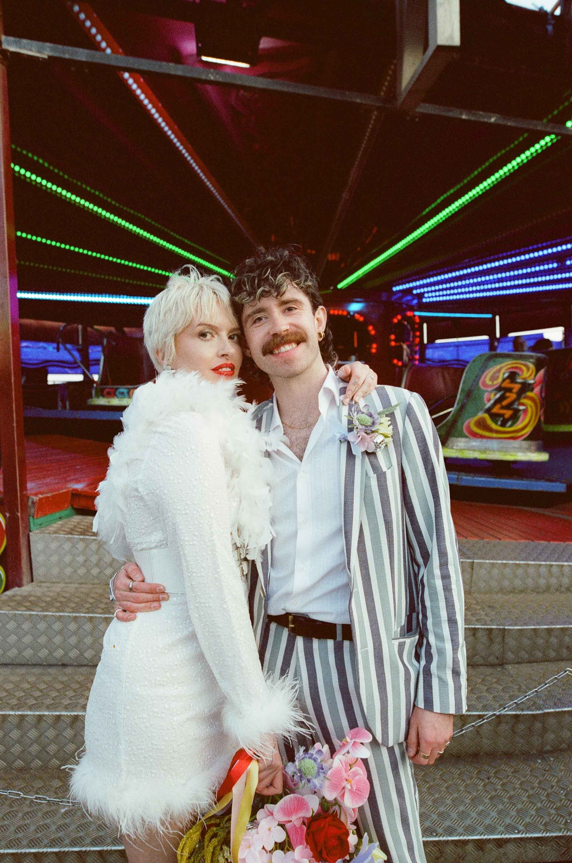 35 mm film photo of a couple stood by a vintage fairground ride