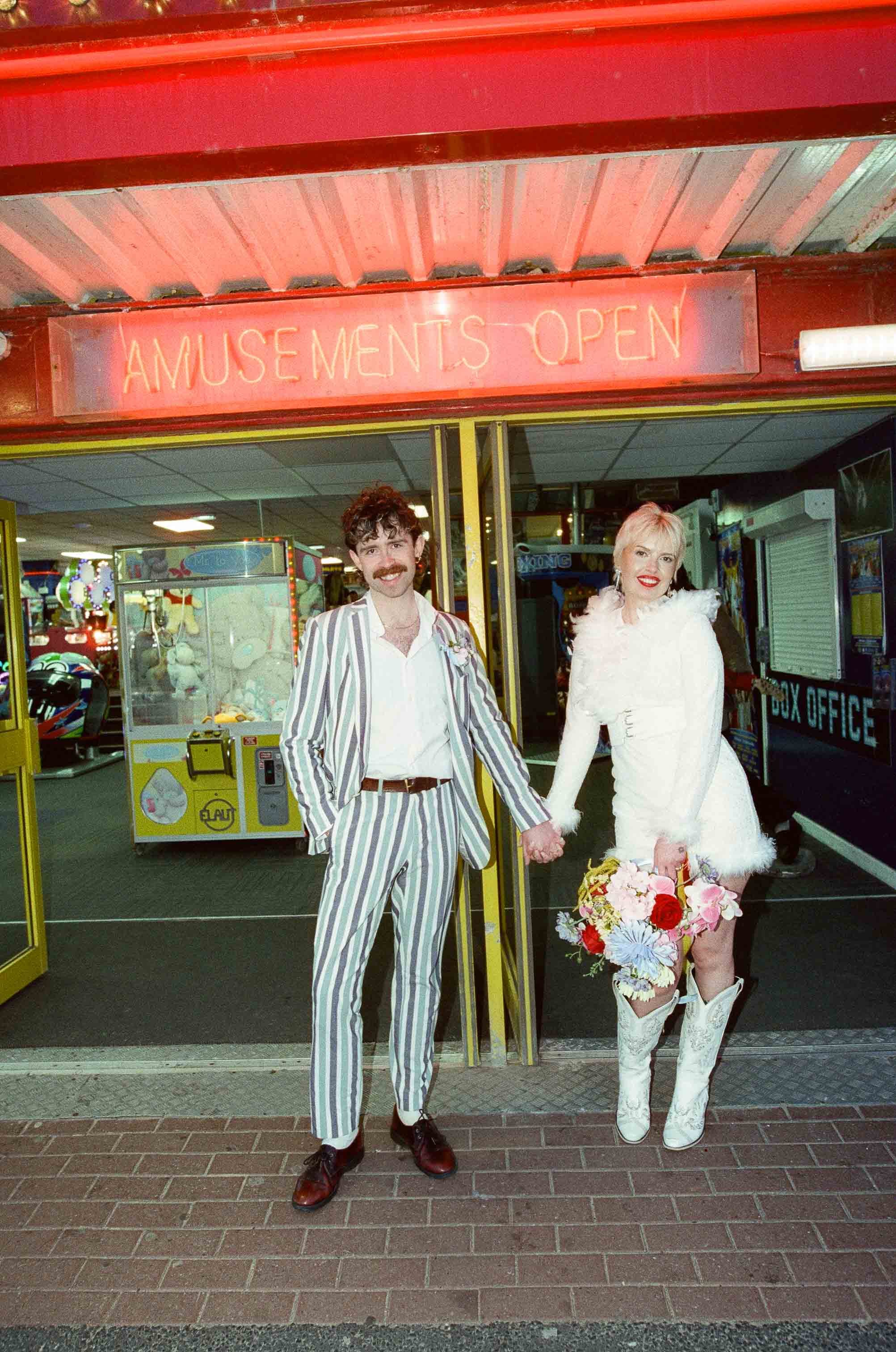 Newlywed couple stood outside an amusement arcade during their elopement