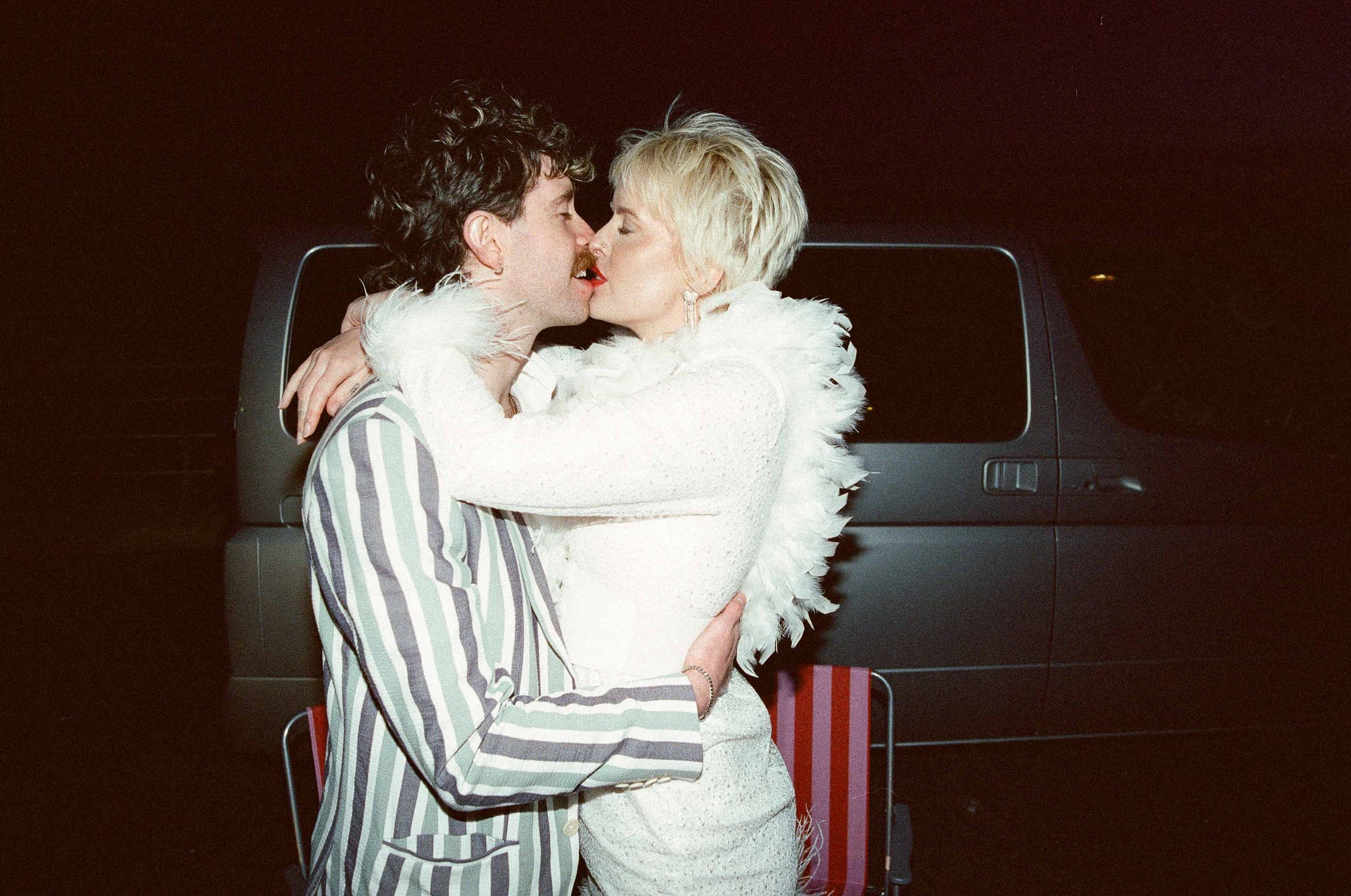 Flash editorial photo of a bride and groom kissing at night on 35mm film