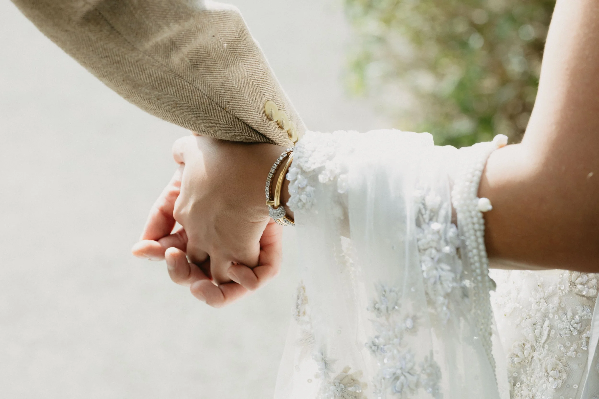 Artistic engagement photo detail - couple holding hands, textured garden backdrop