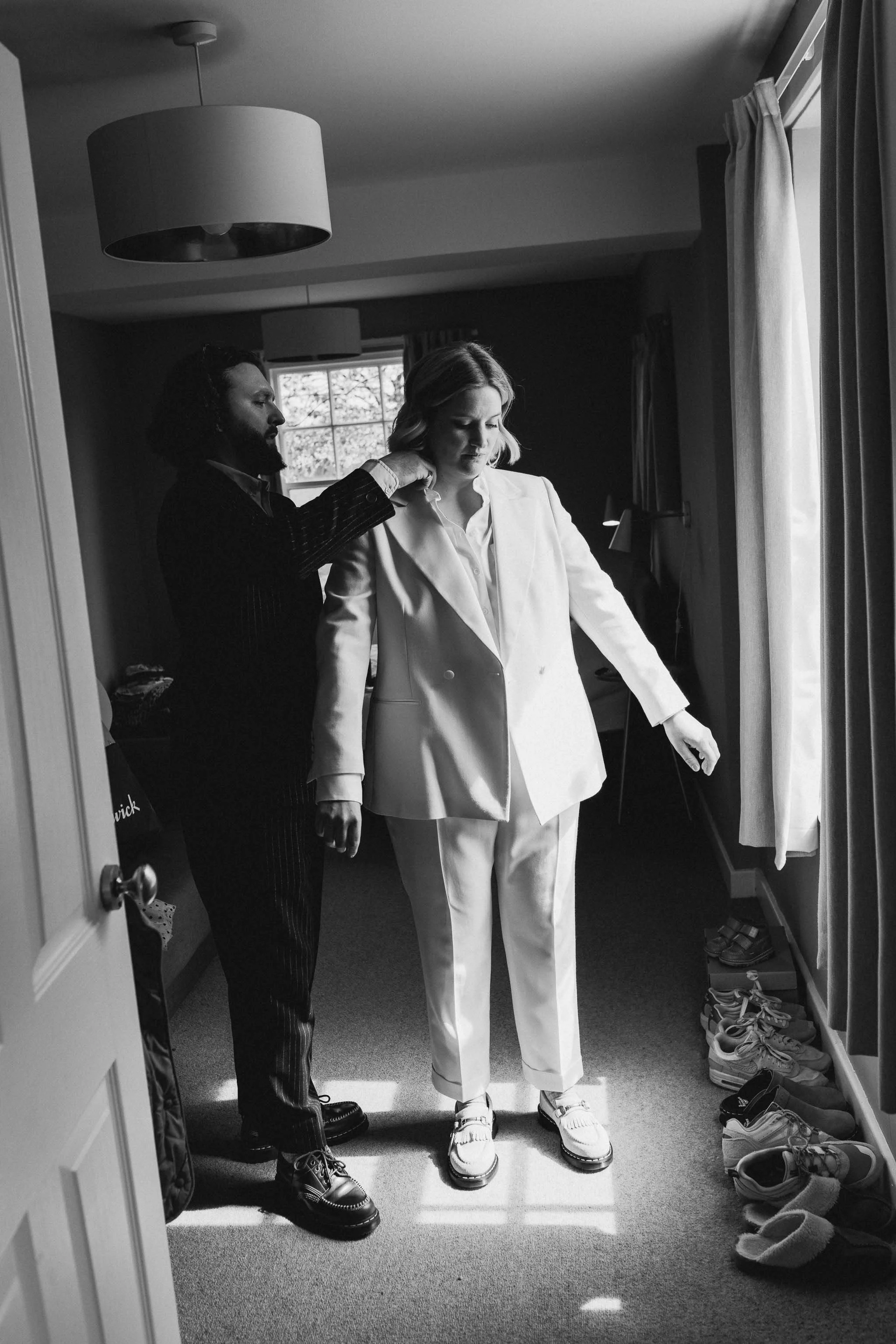  Tailored suit being adjusted in soft light on the wedding morning. 