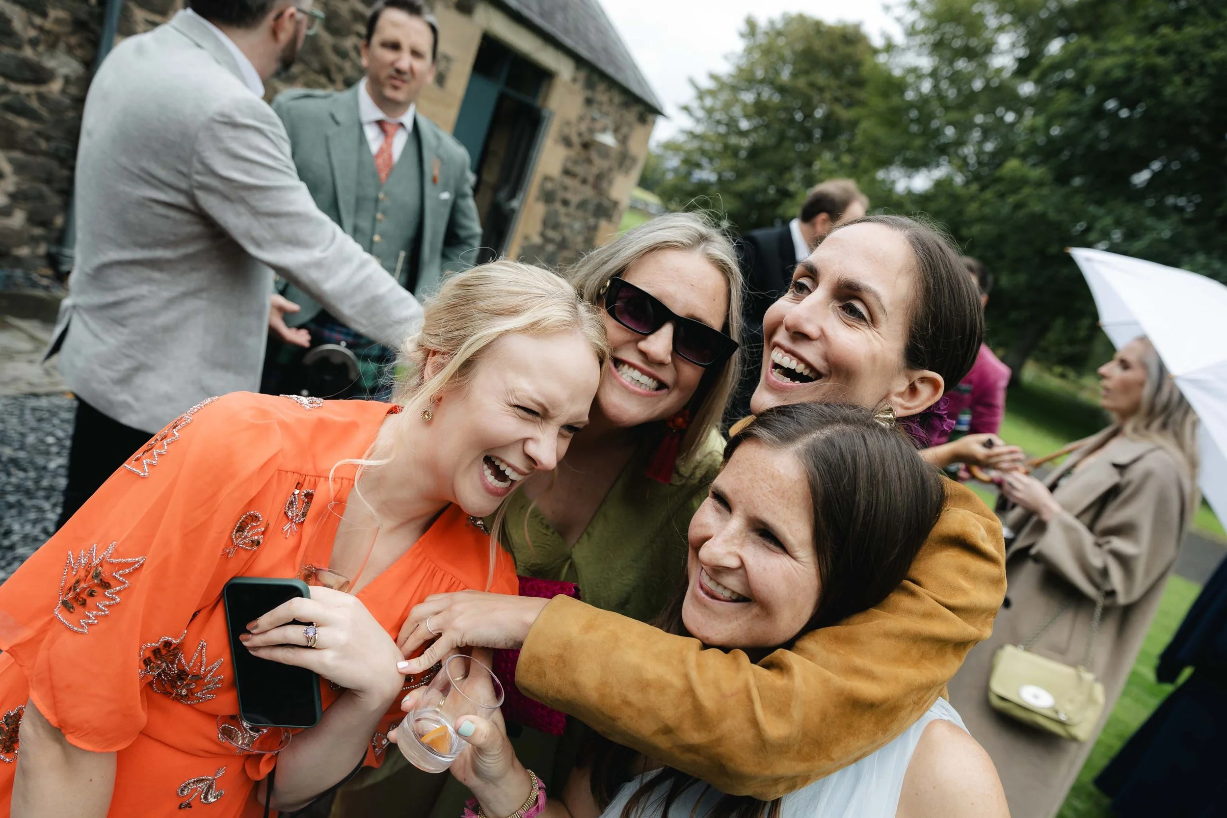  Wedding guests huddled together laughing. 