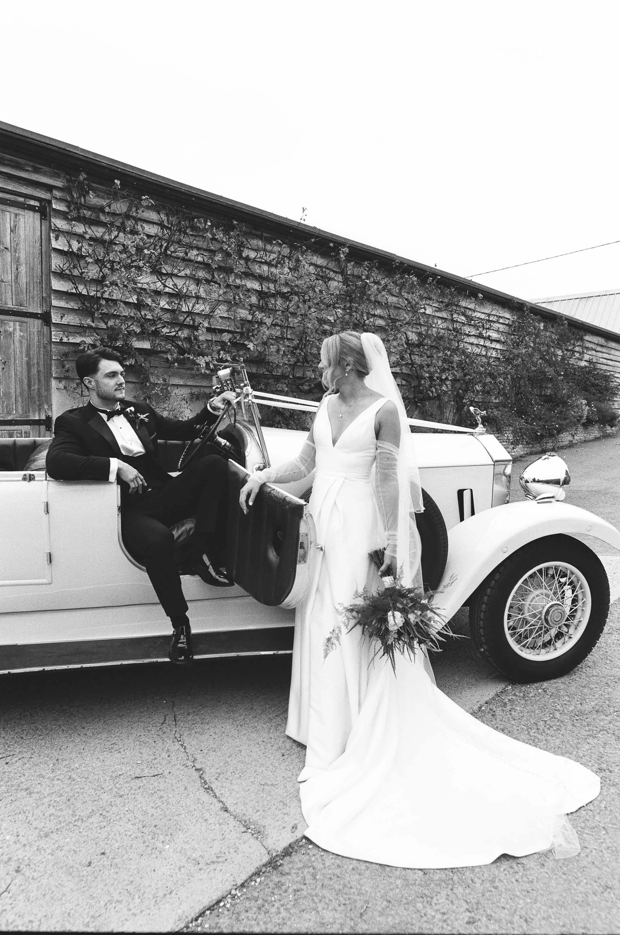  Bride and groom relaxed wedding portrait in a classic car. 
