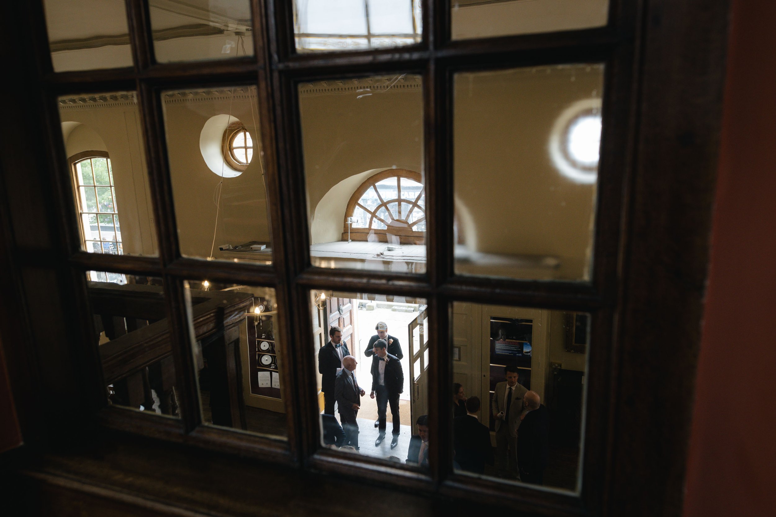  Documentary wedding photo of wedding guests taken through an indoor window. 