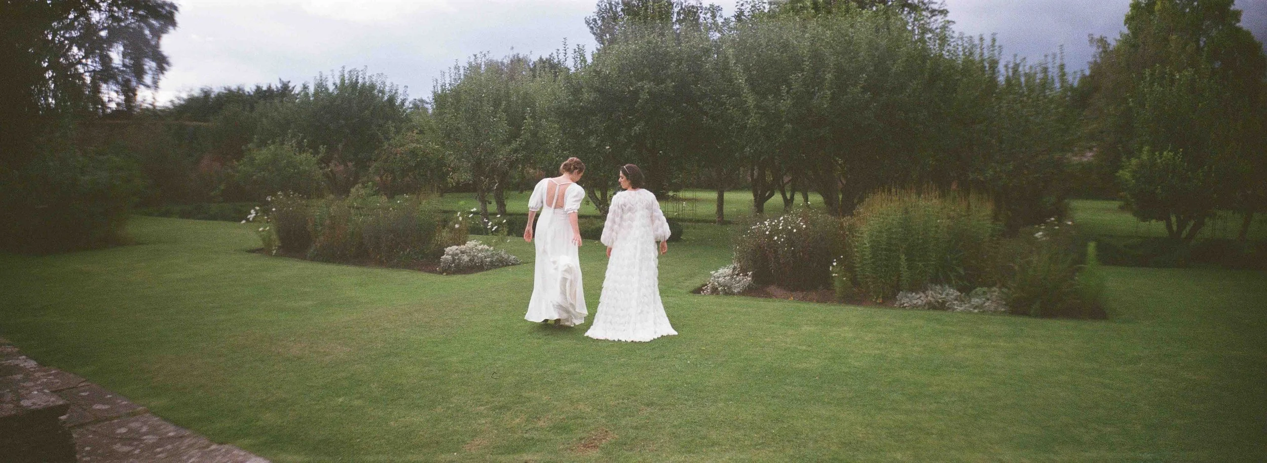  35mm film photo of a wedding couple walking together in landscaped gardens. 