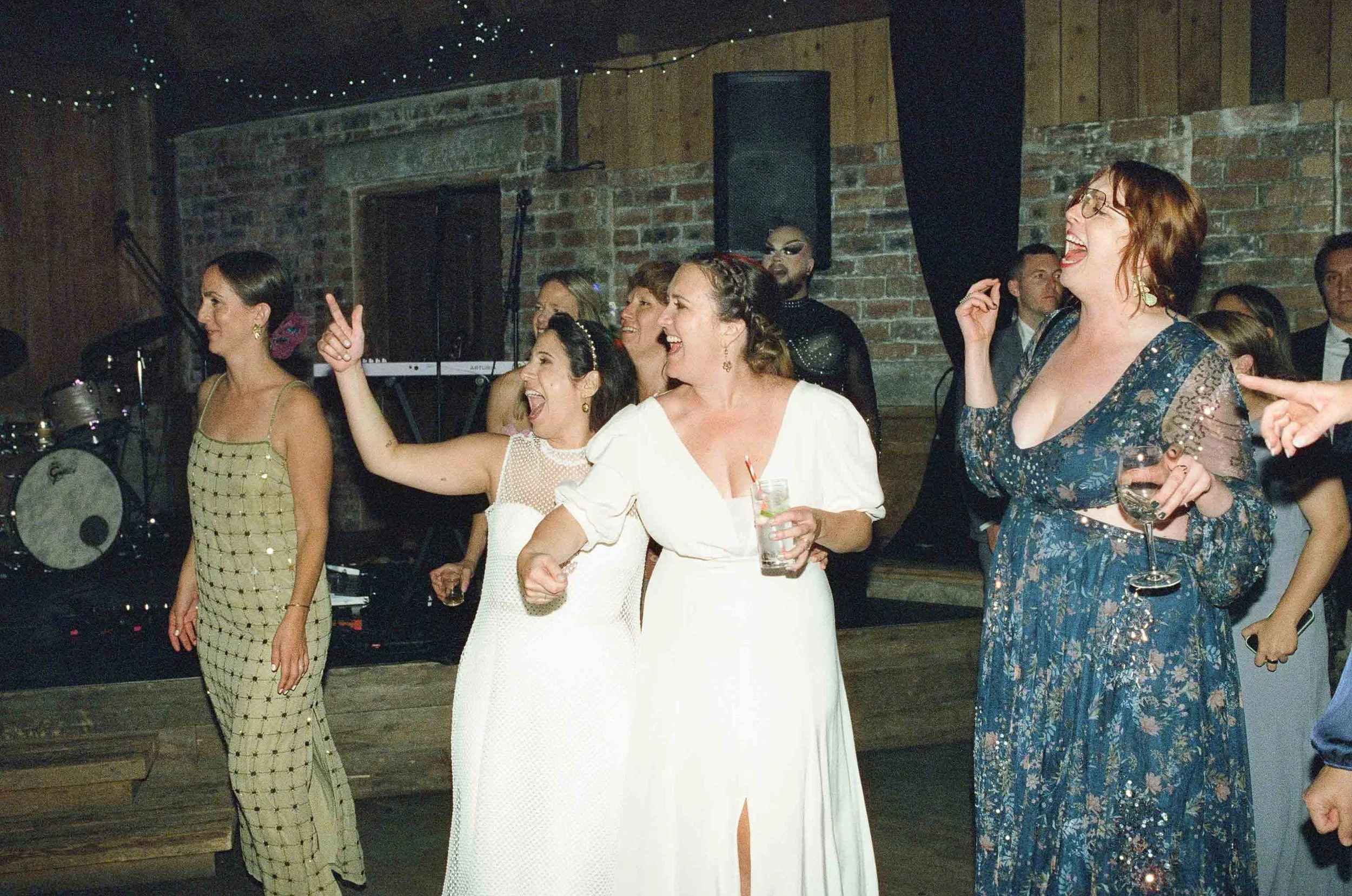  Two brides and guest cheering on the dance floor. 