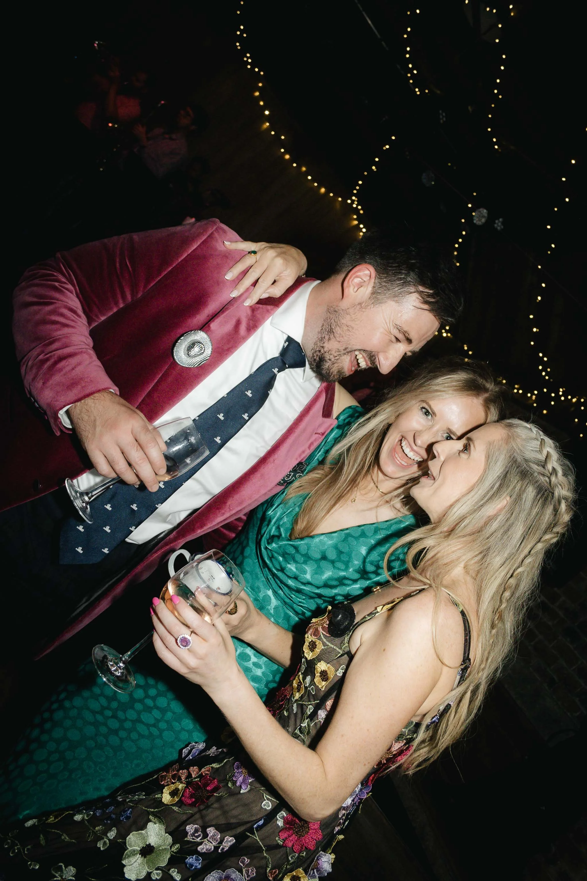  Wedding guests huddled together laughing on the dance floor. 