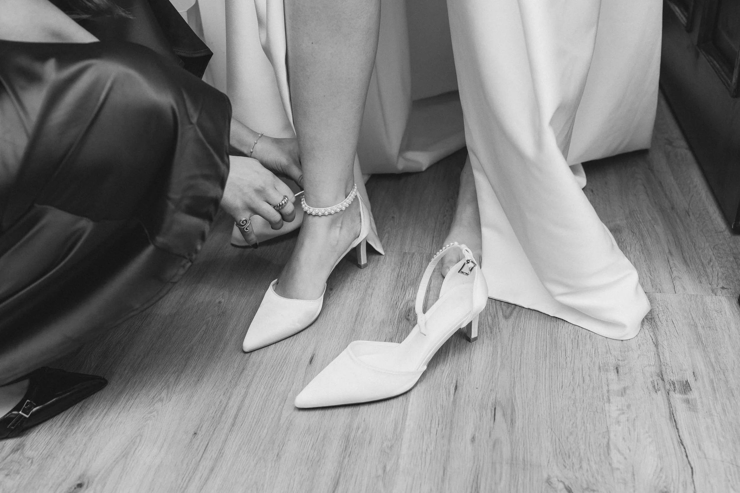  Black and white storytelling shot of a bride putting on her shoes. 