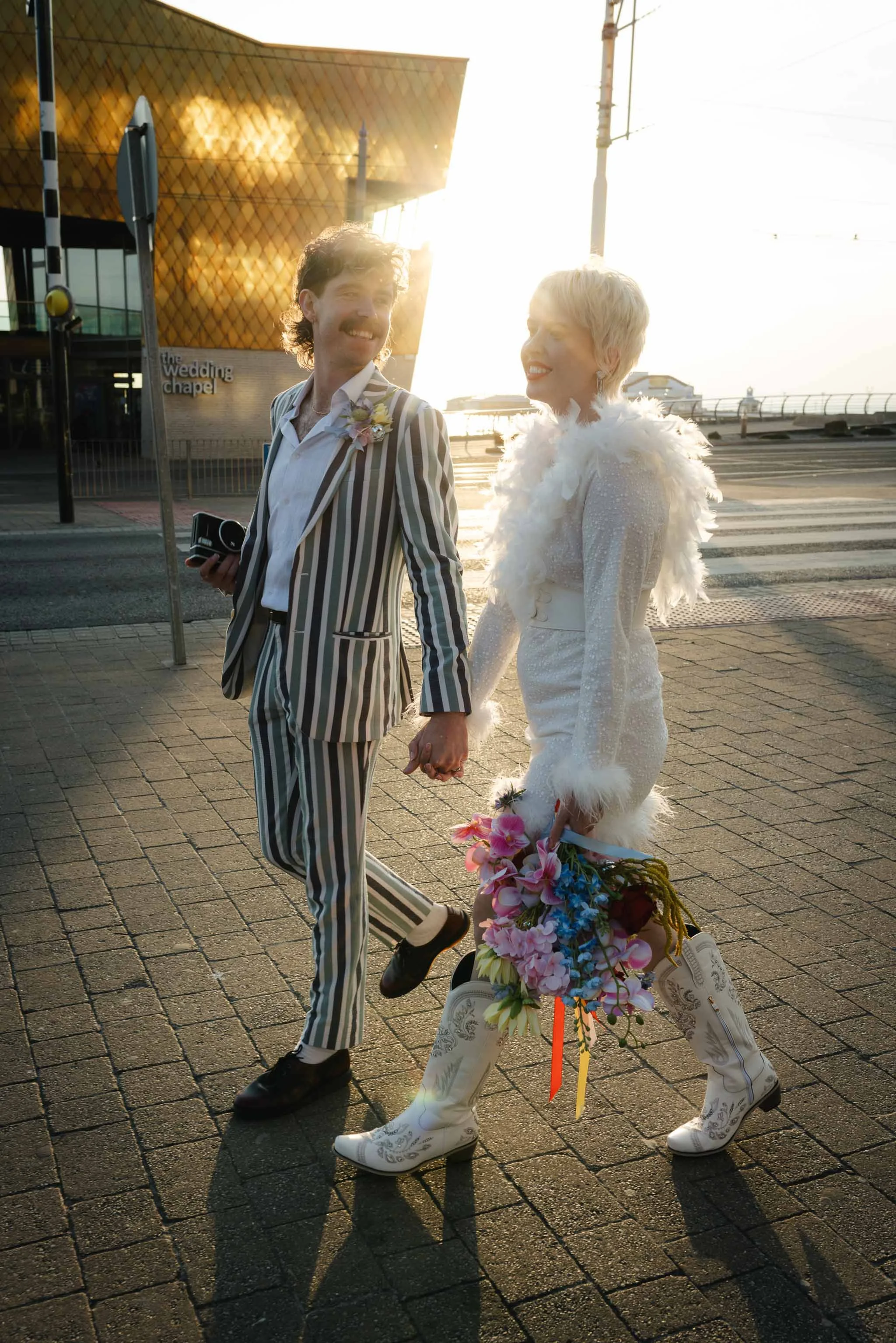  Wedding couple walking hand in hand during sunset on Blackpool sea front.  