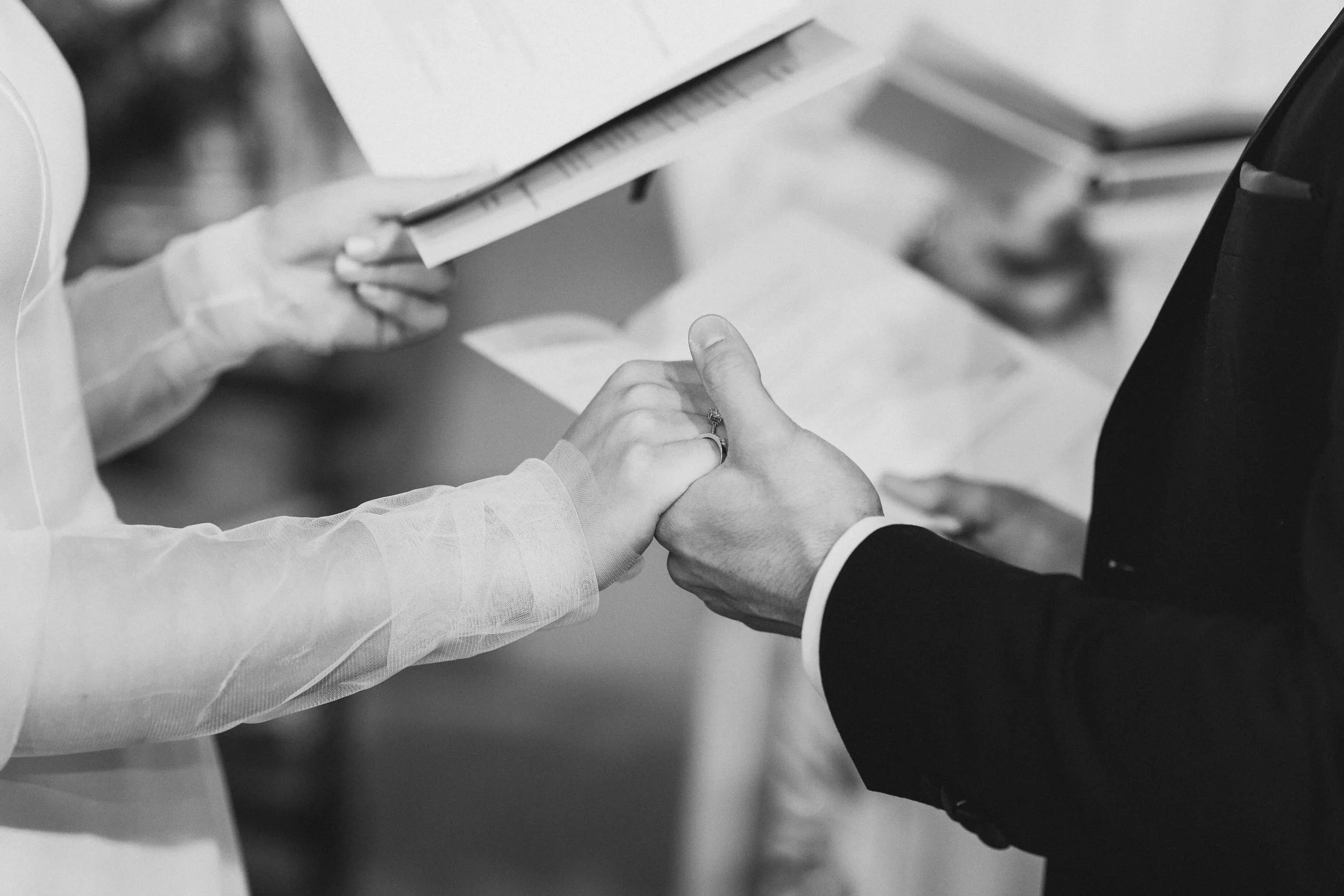  Documentary photo of a couple holding hands during their wedding ceremony. 