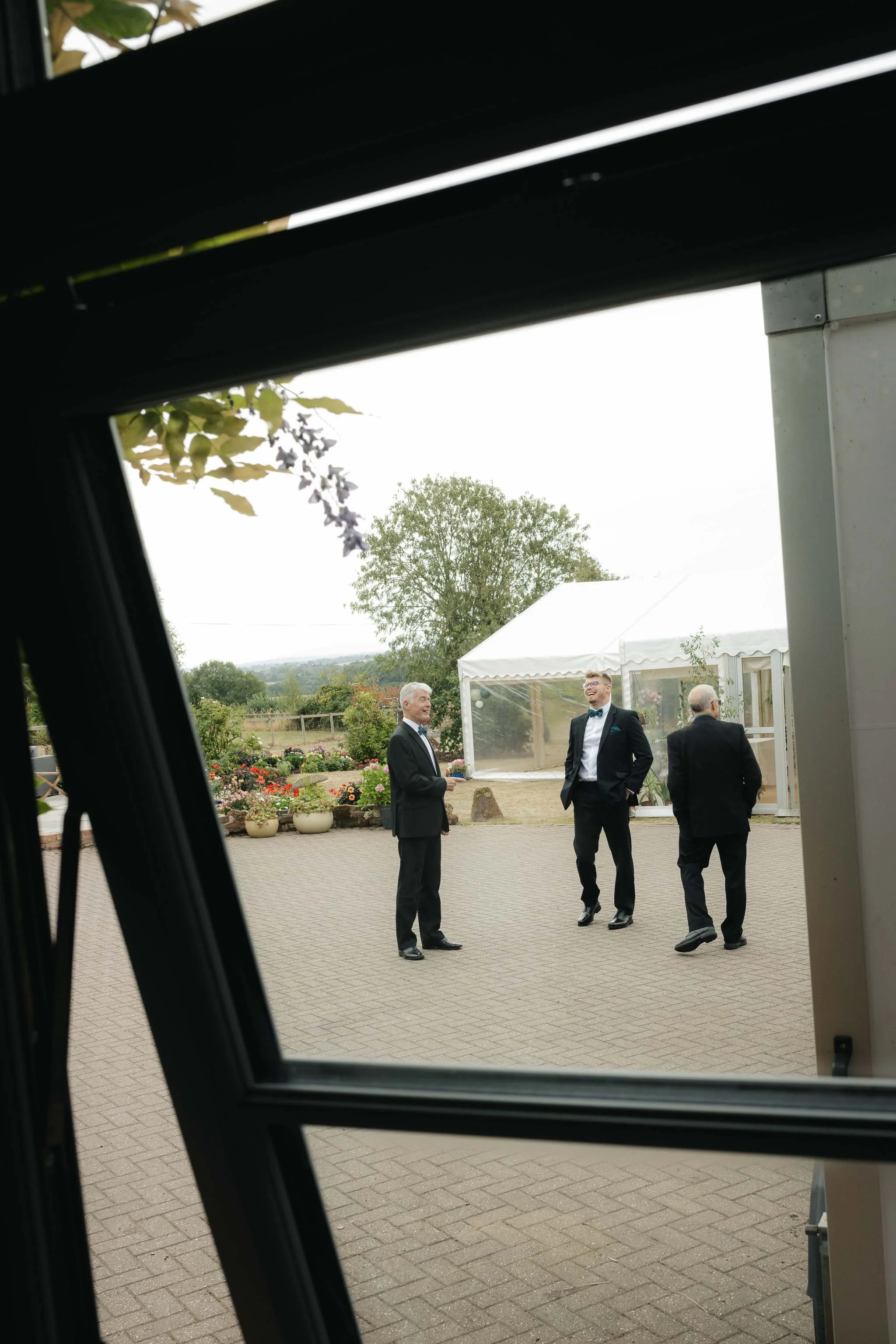  Groom and groomsmen stood laughing through a window. 