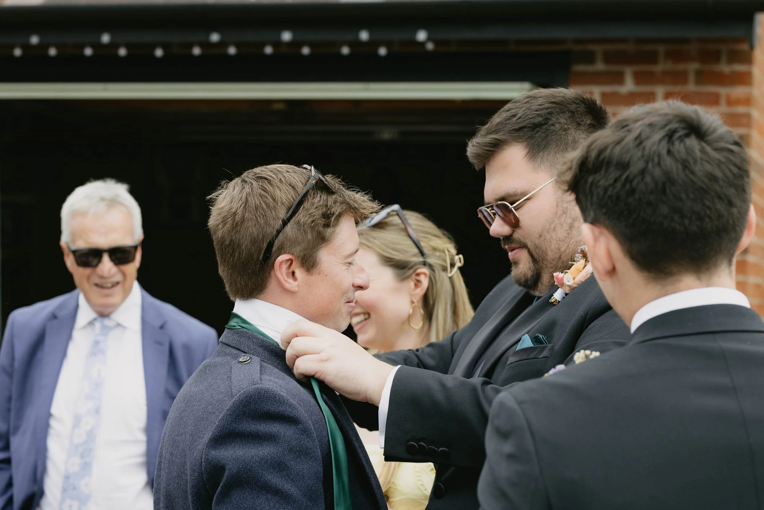  Guest helps someone with tie during a backyard wedding reception in Worcester. 