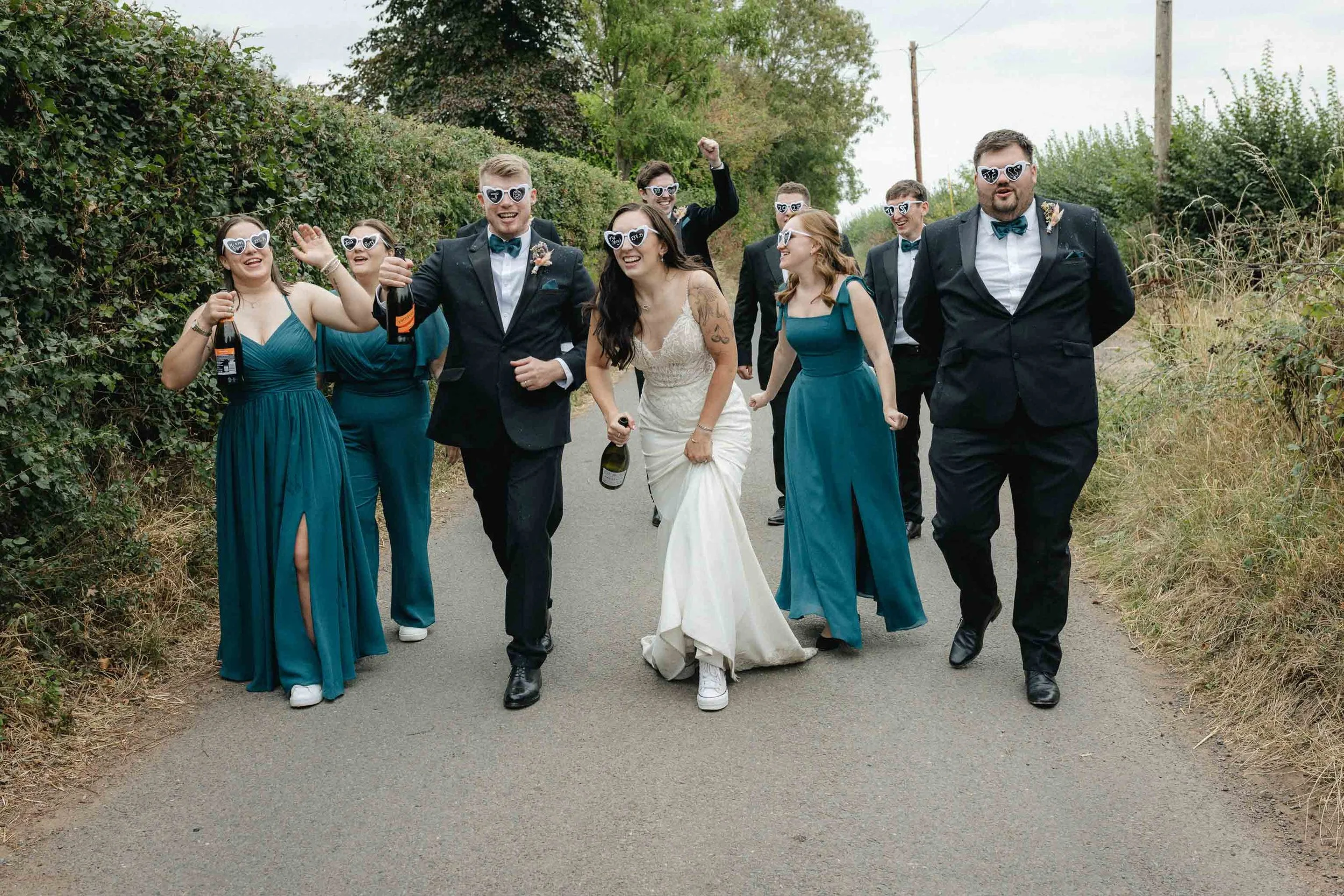 Jess + Oli laughing together after spraying champagne with their bridal party at Worcester wedding.   