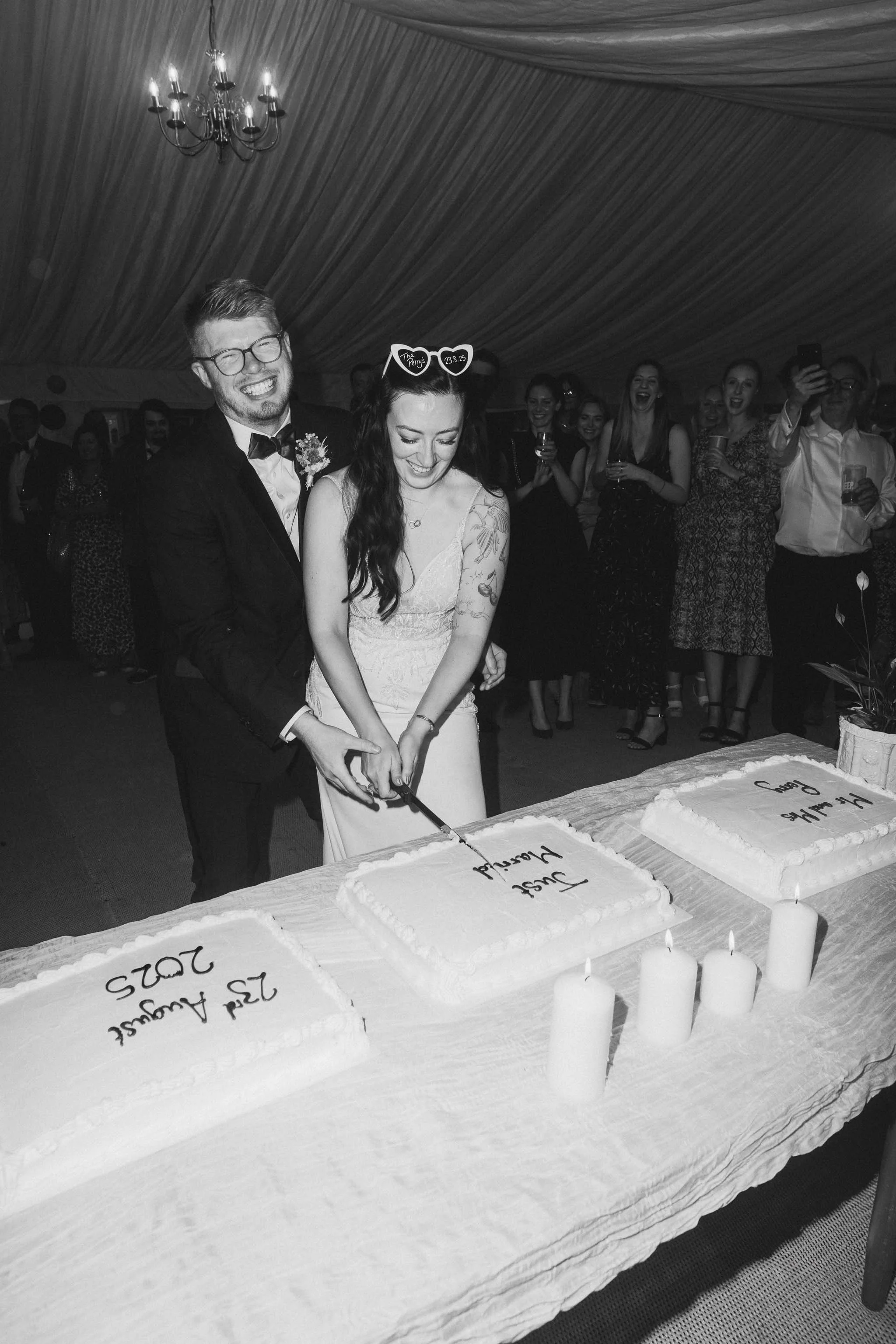  Bride and groom sharing cake-cutting moment at Worcester wedding marquee.   