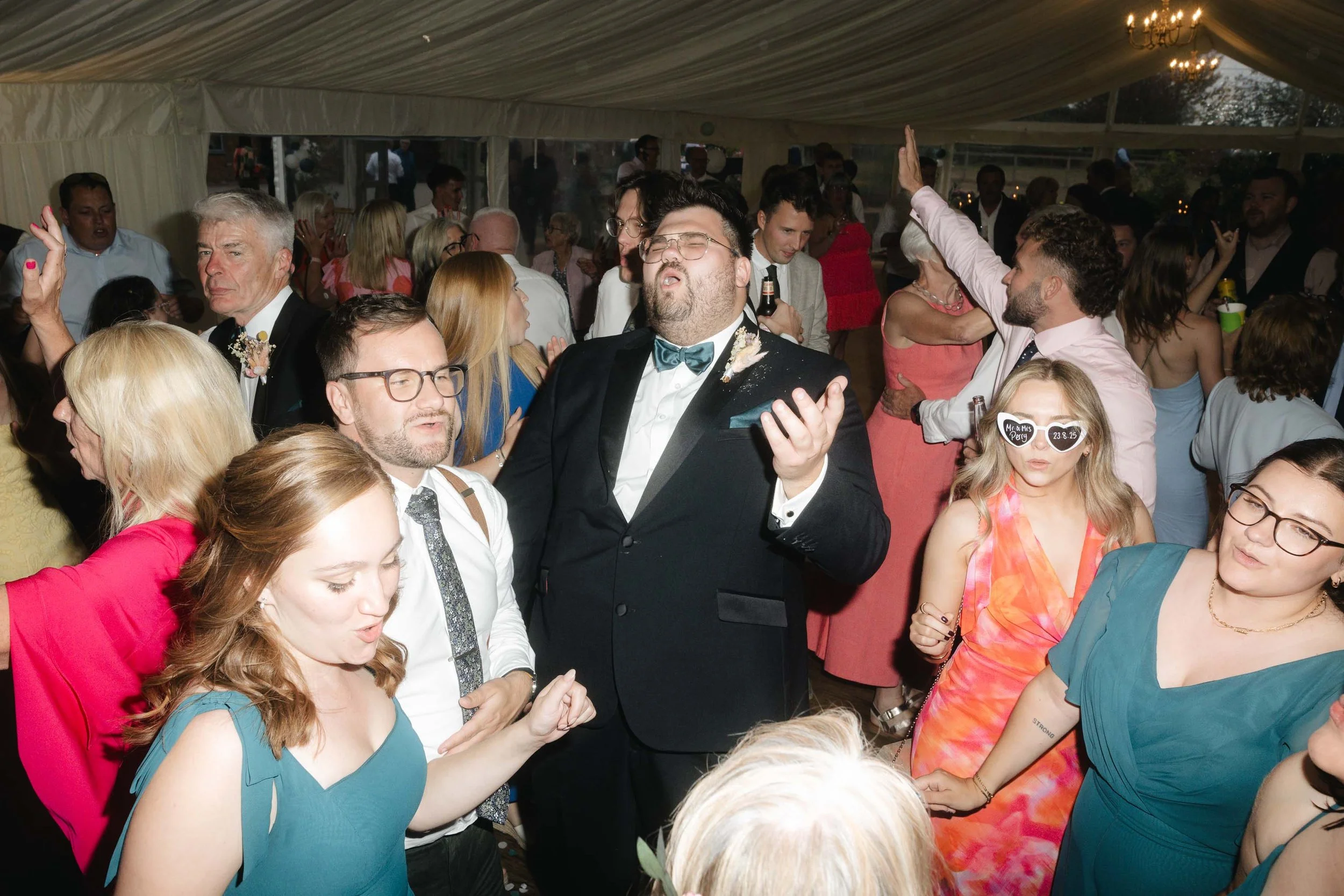  Candid moment of wedding guests celebrating at Worcester wedding marquee.   