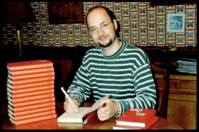 FIGURE 1. At the oval, pine dining table, signing copies of my first book for family and friends. Photo taken at my father’s insistence; smug expression, entirely down to me.