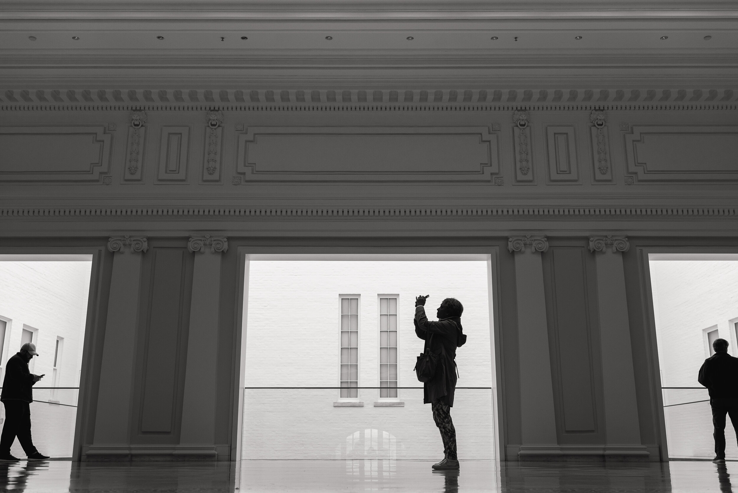 A woman takes a photograph of architecture at the Carnegie Library and Apple Store in Washington, D.C.