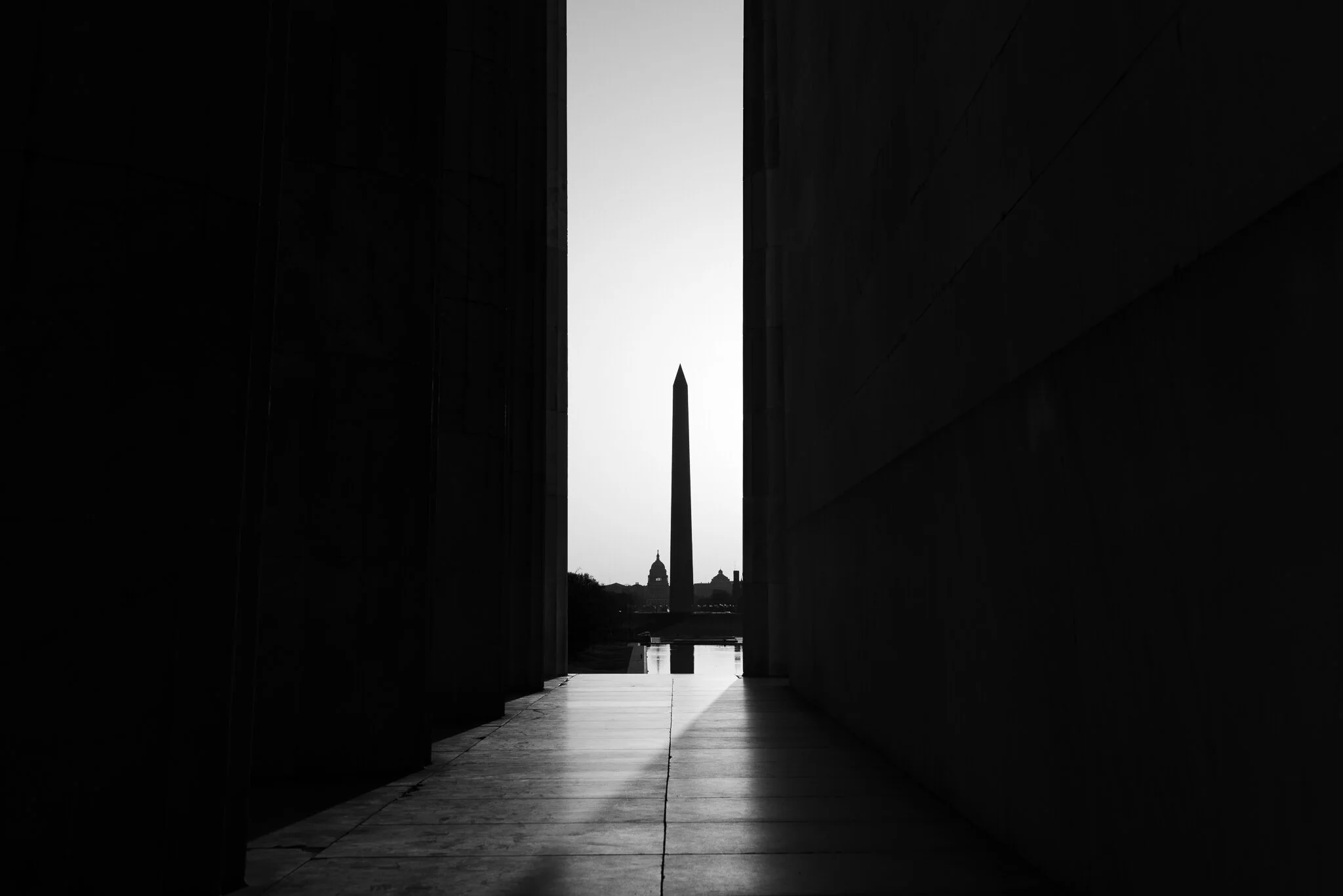 Black and white photo of the Washington Monument and U.S. Capitol from the columns of the Lincoln Memorial.