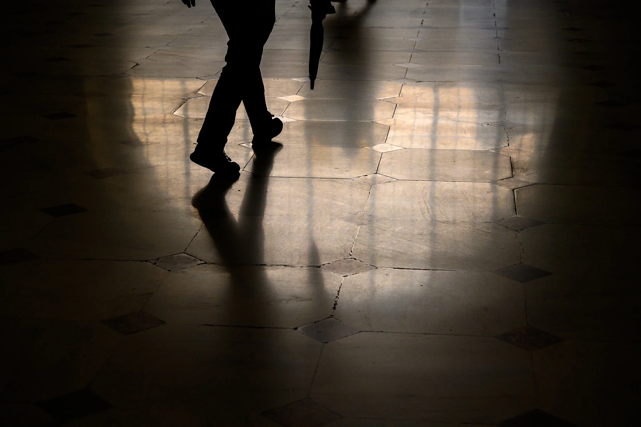 Reflection of a man carrying an umbrella in Washington, D.C.'s Union Station.