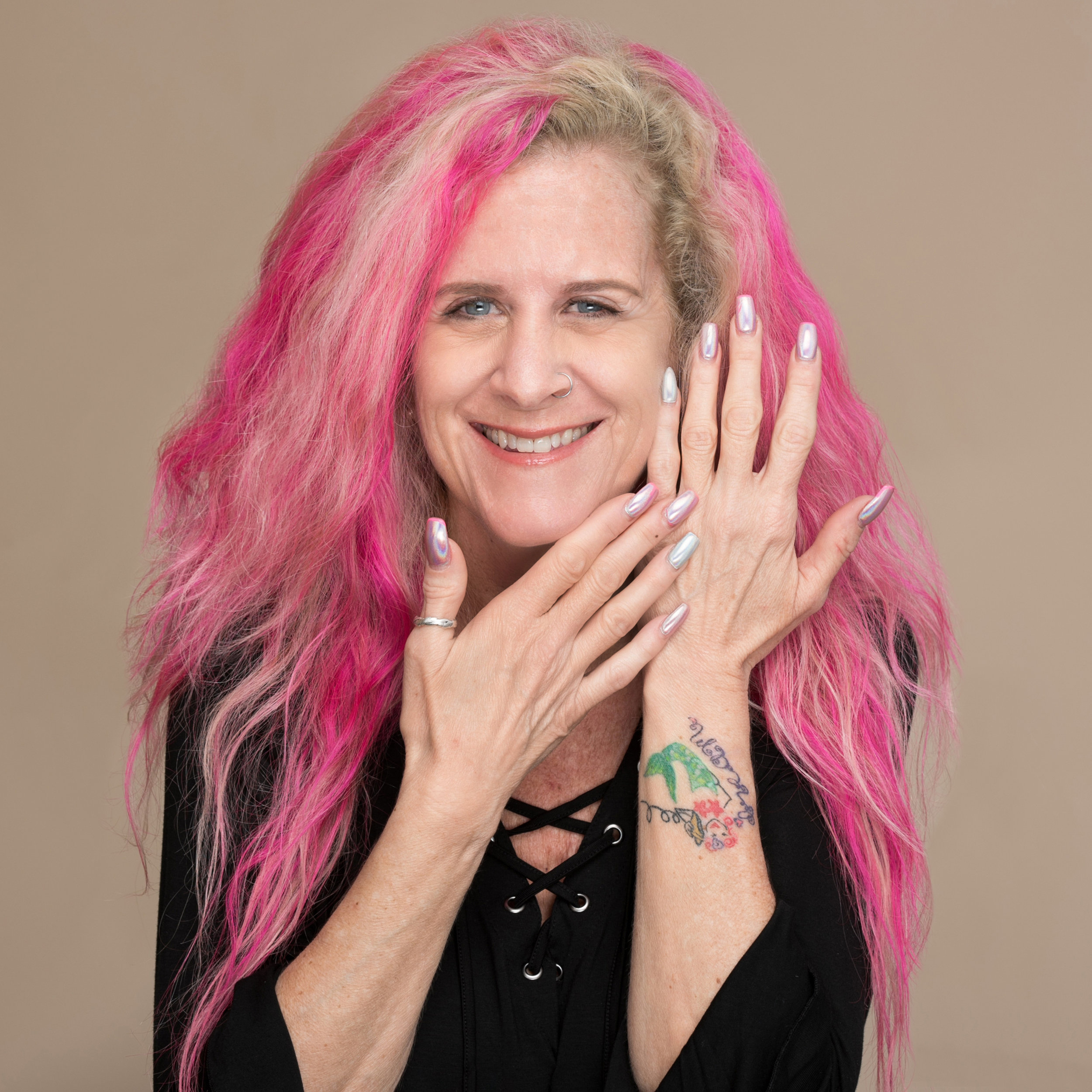 Smiling pink haired nail stylist displaying her colorful nails