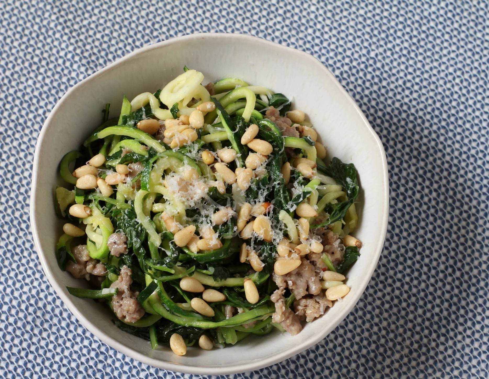 Aerial view of zucchini noodles with sausage and kale.  