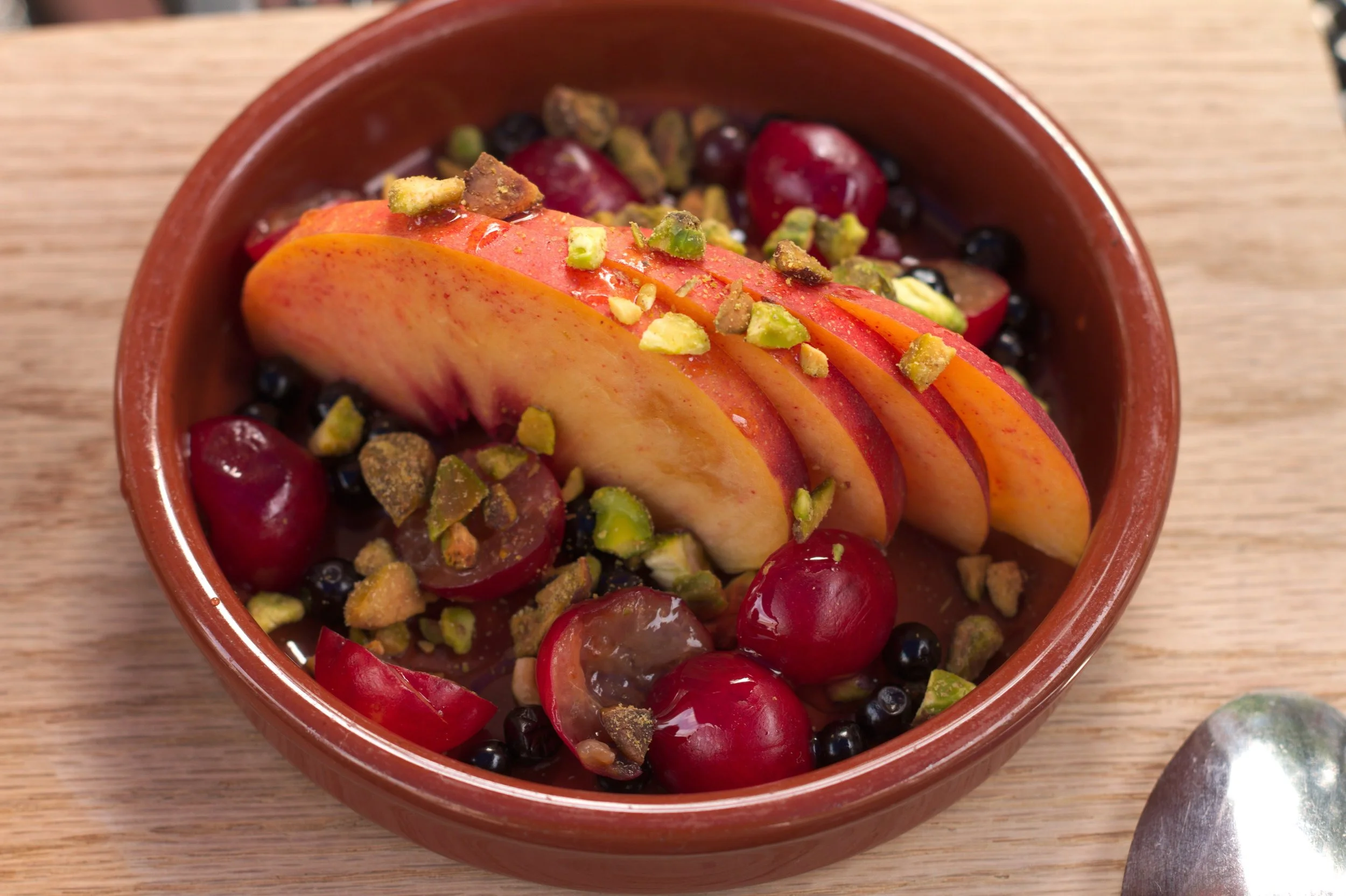 Sliced peaches with pistachios and sour cherries.